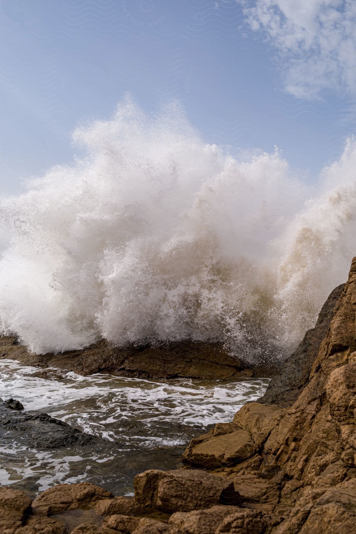 Ocean waves crashing against a rocky mountain near the shore