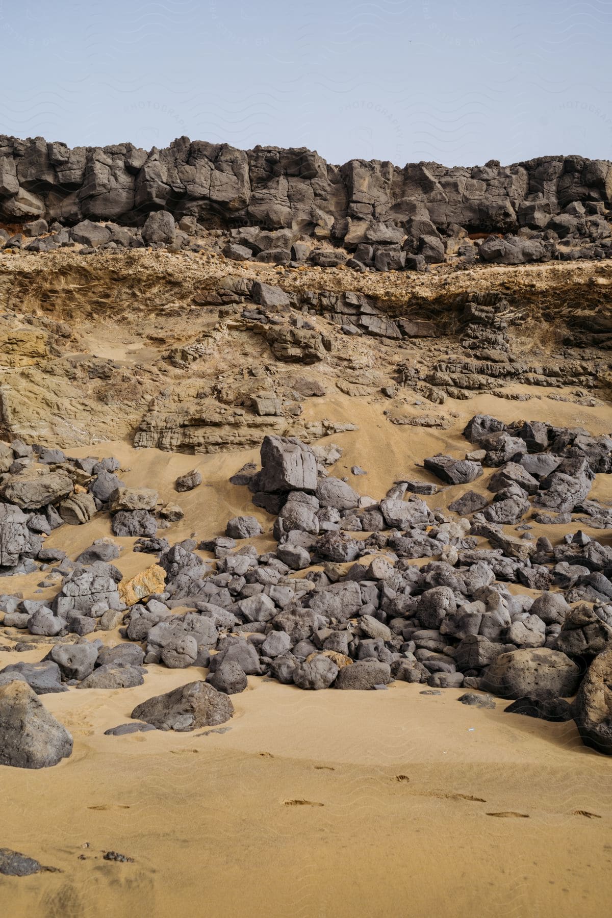 Rocks at the bottom of a rocky cliff above the sand