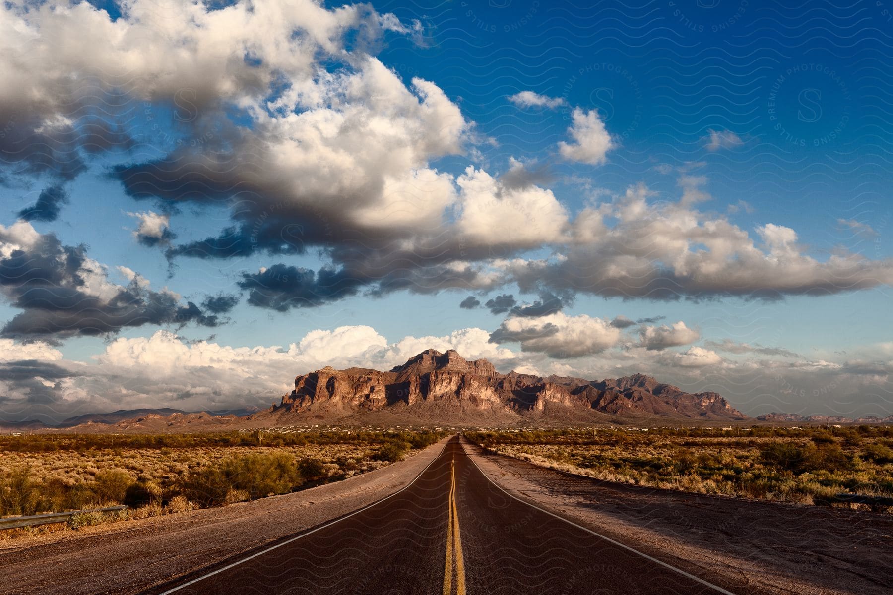 A highway stretches across the plains toward a mountain in the superstition mountains in apache junction late in a december afternoon