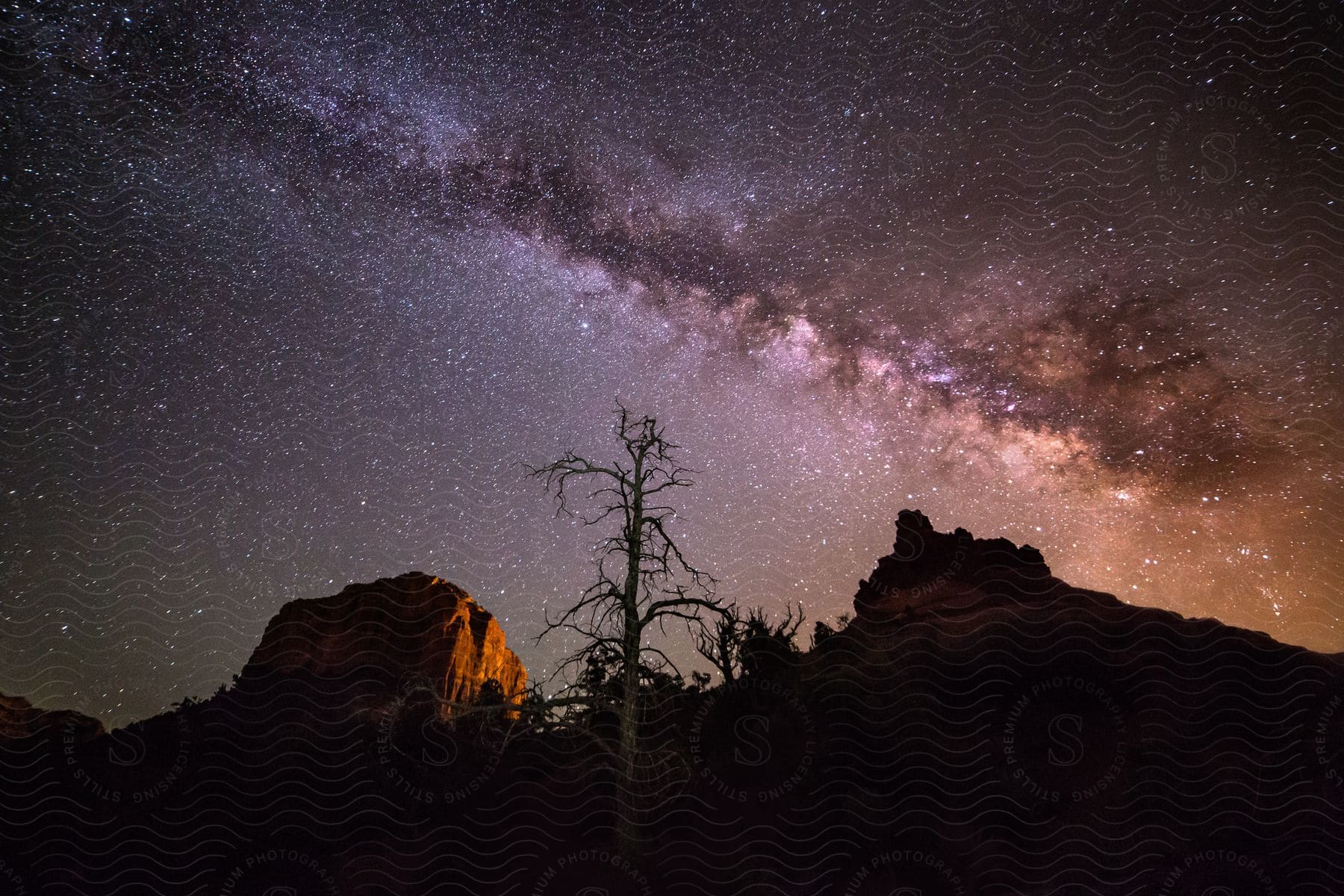 Stars and long cloud over red rock desert plateau at night