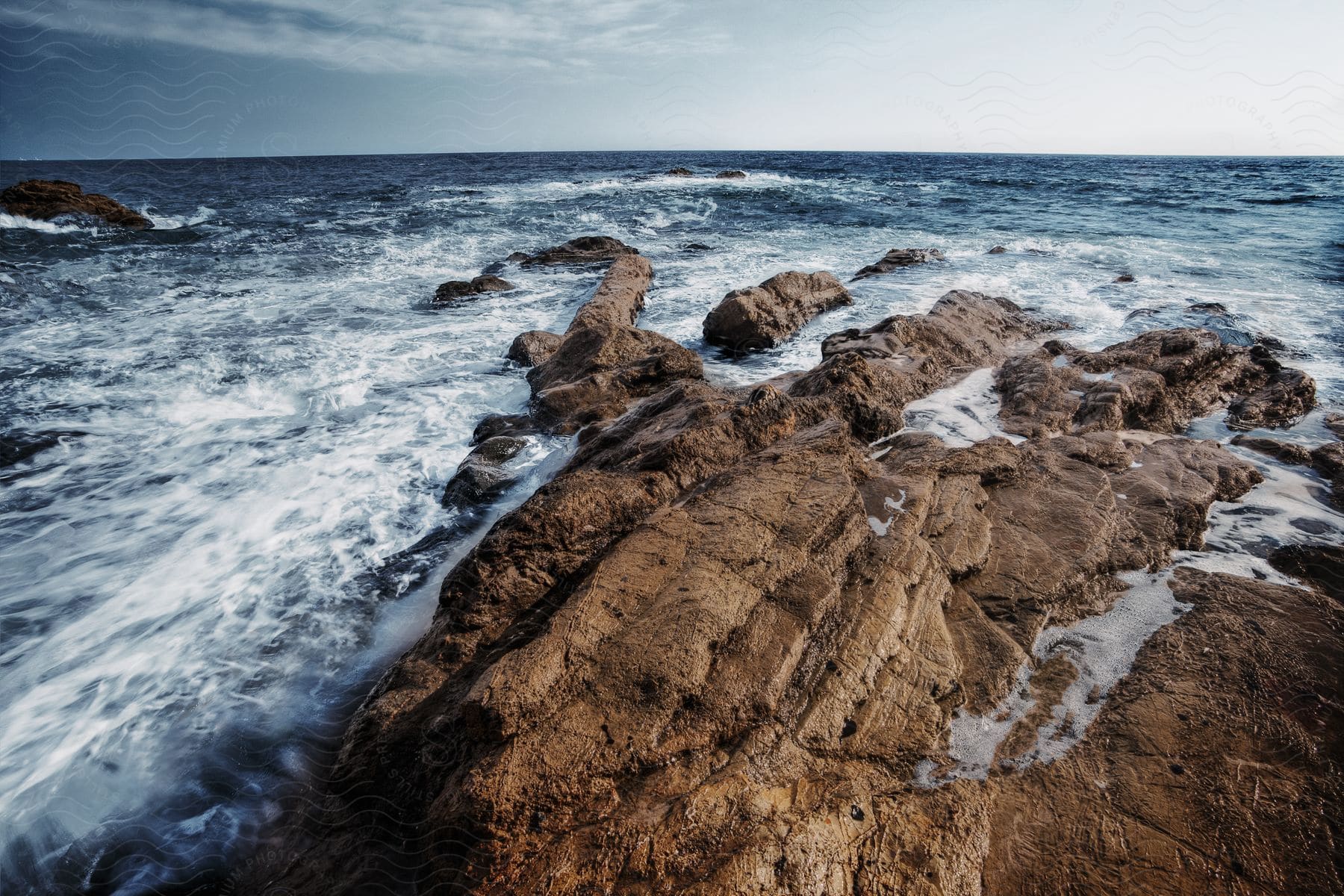 Ocean waves crashing against rocks on the shore along the coast of california off the pacific coast highway just north of los angeles