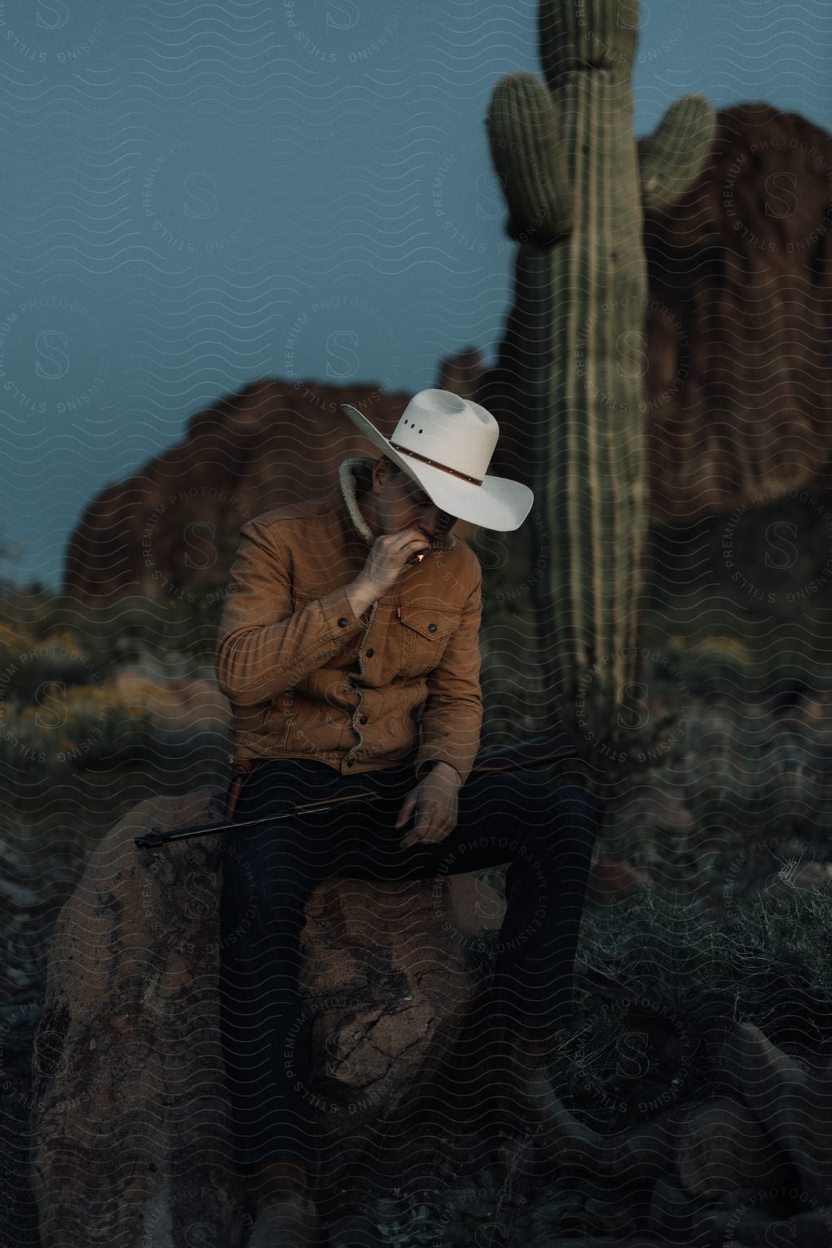 A person wearing a sun hat sitting on a rock