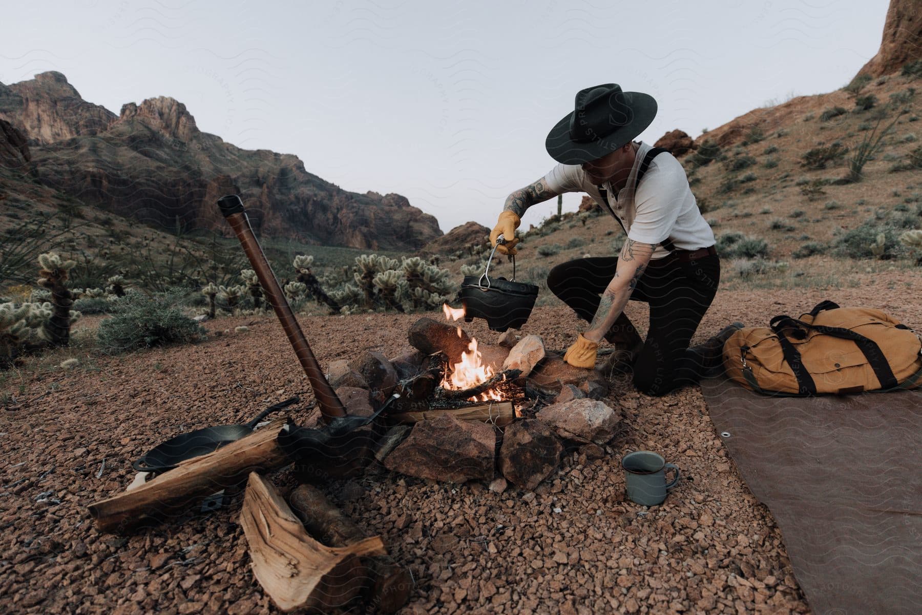 Cowboy cooking over a campfire in the badlands at dusk