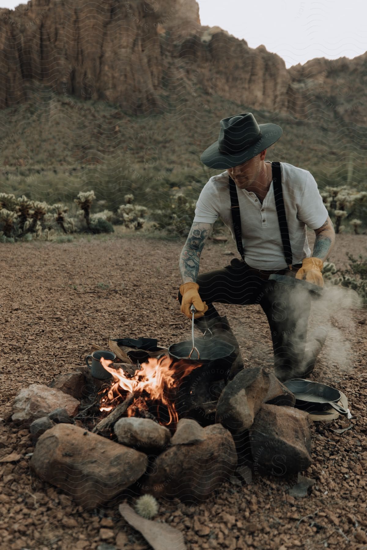 A Person Wearing A Hat Standing Outdoors In Front Of A Mountain