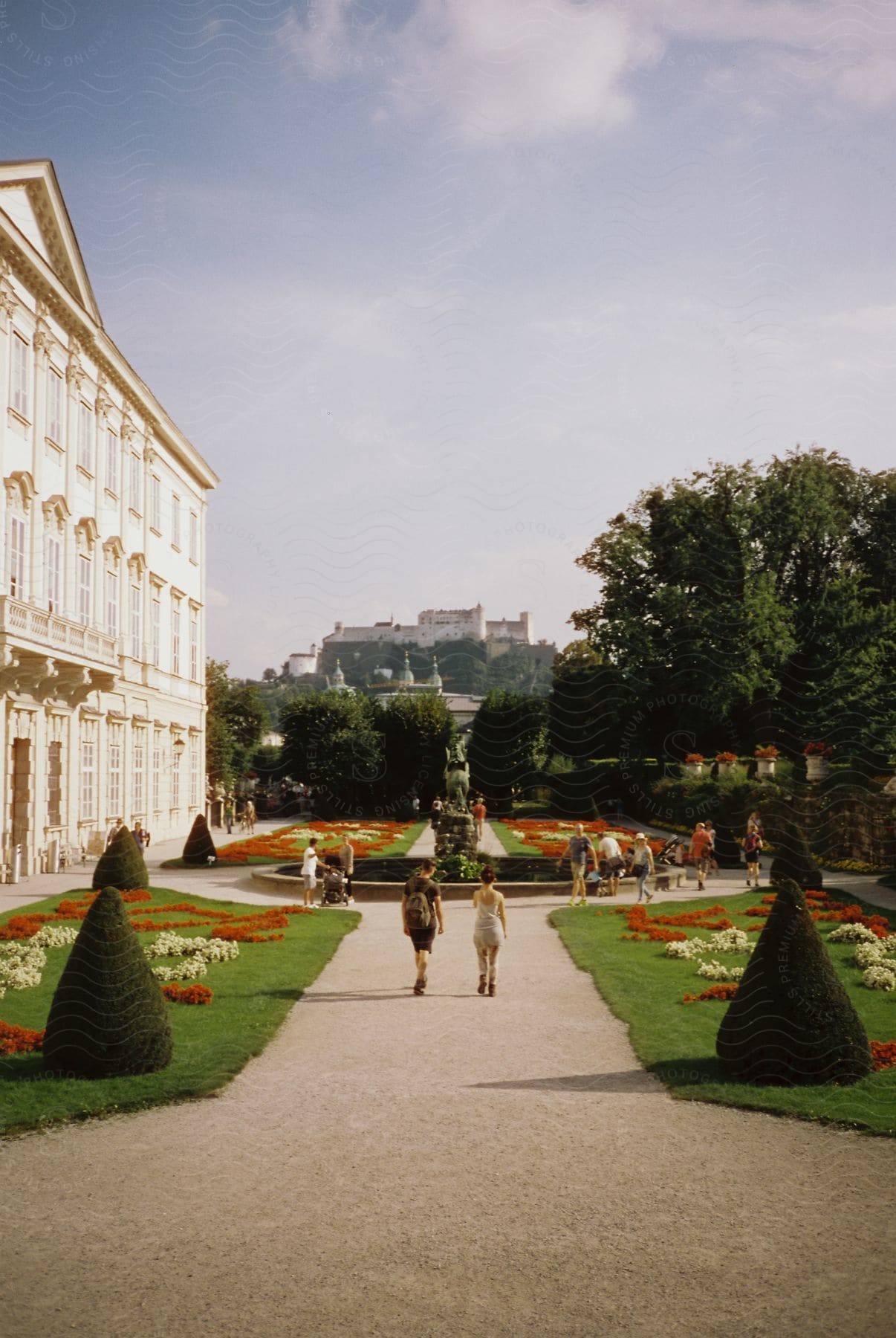 People walking on a courtyard path in front of a white building