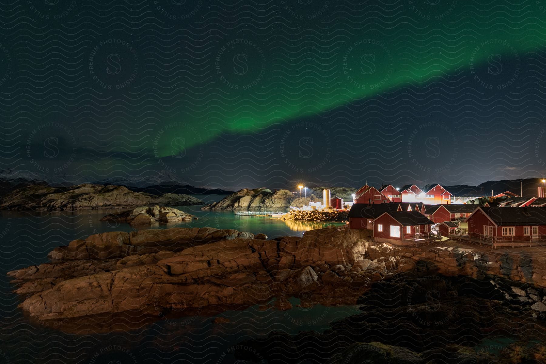 A coastal town is visible beneath the northern lights