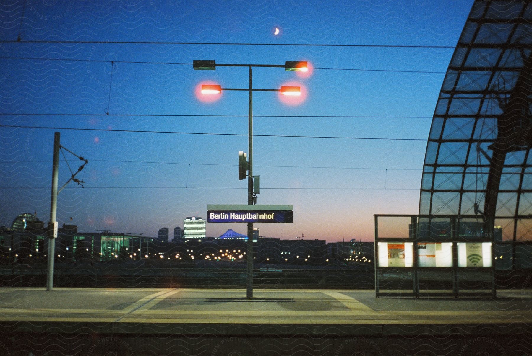 The berlin railway station is partially shown against the night sky and the city below it