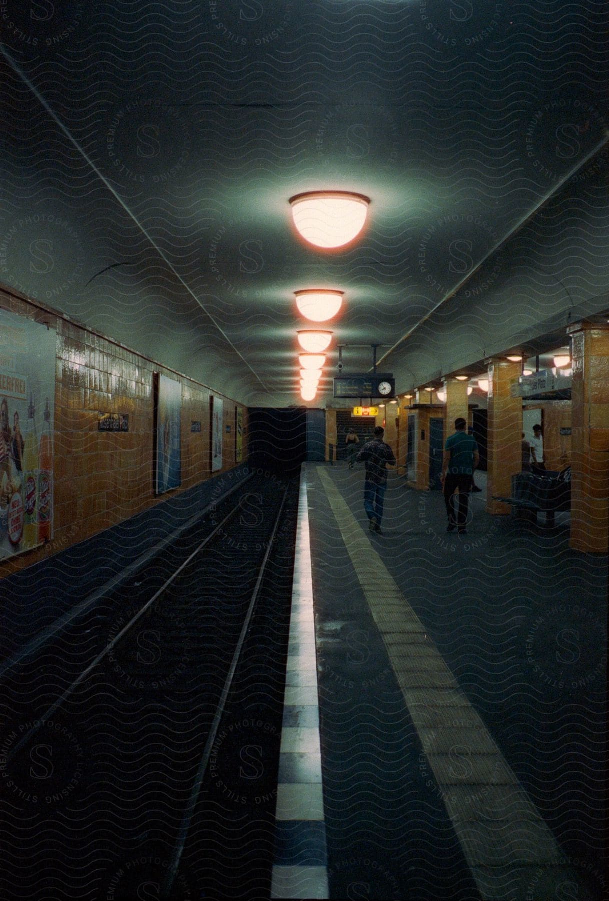 People walk towards a stairwell to exit a dim subway station