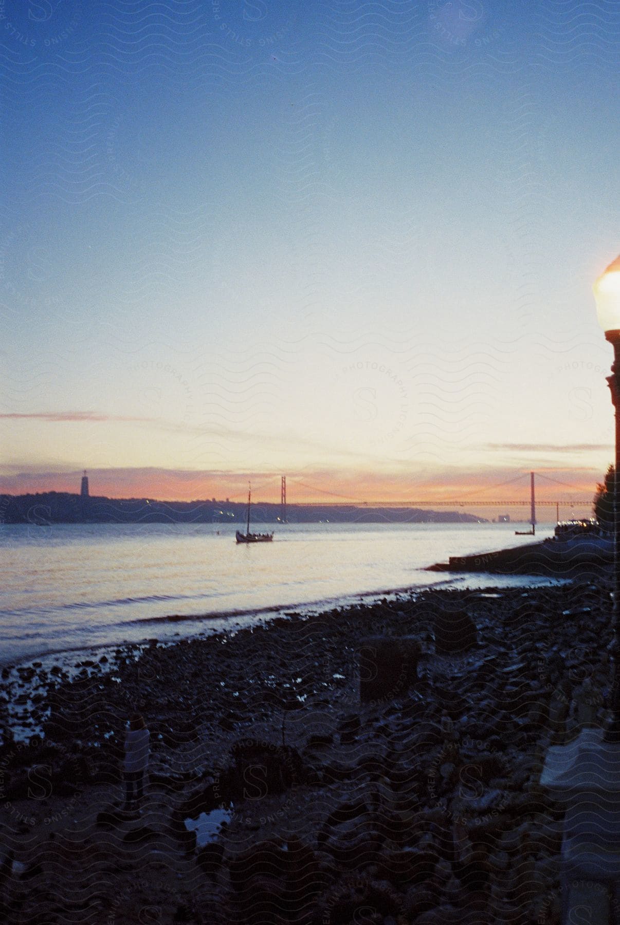 A boat floats near the beach at dusk