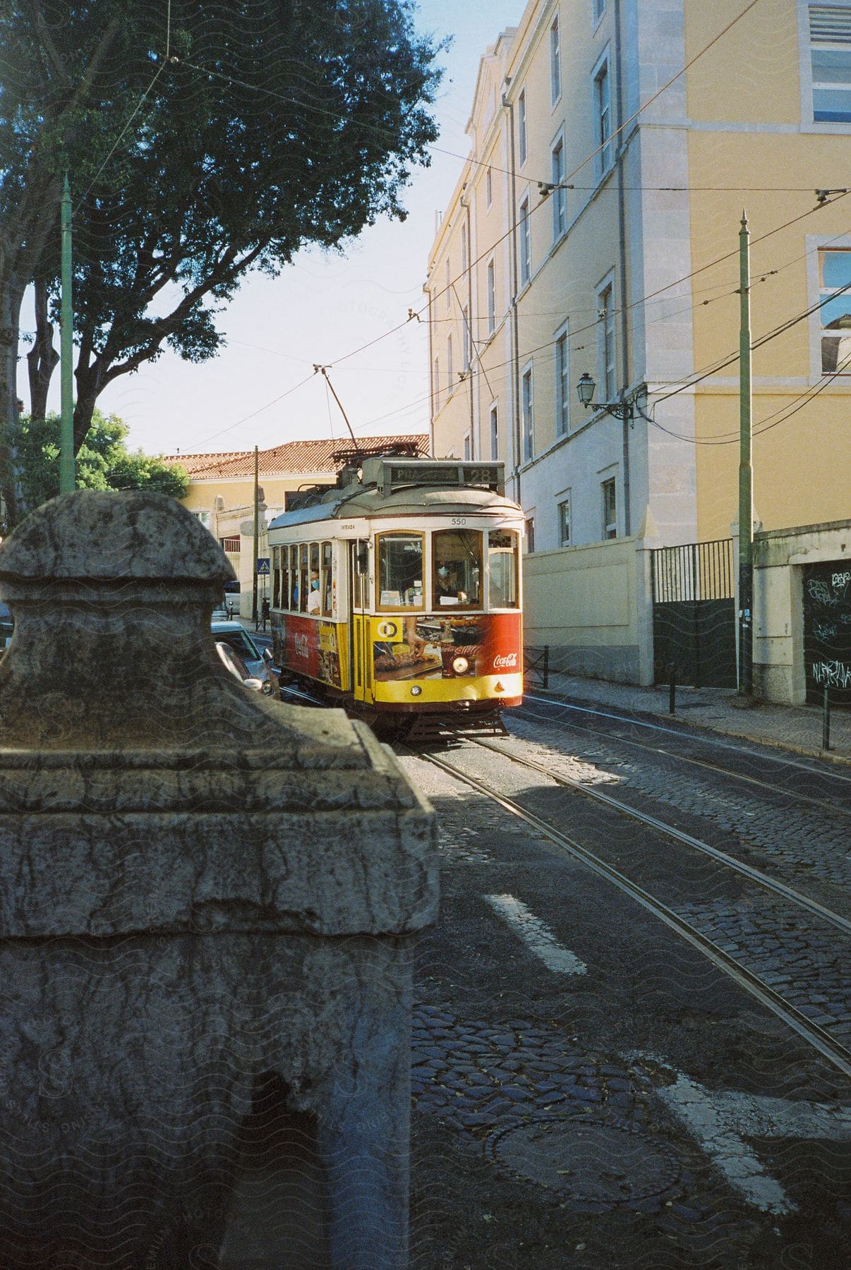 A cable car passes by a yellow multistory building under blue skies