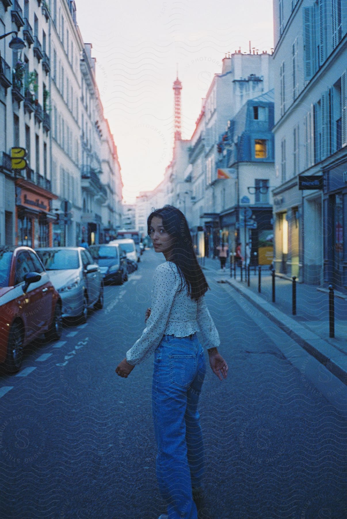 A girl standing in a city street surrounded by buildings and cars