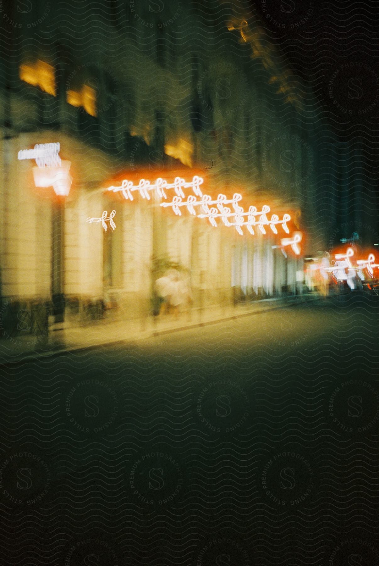 A city building with bright lighting next to a street at night