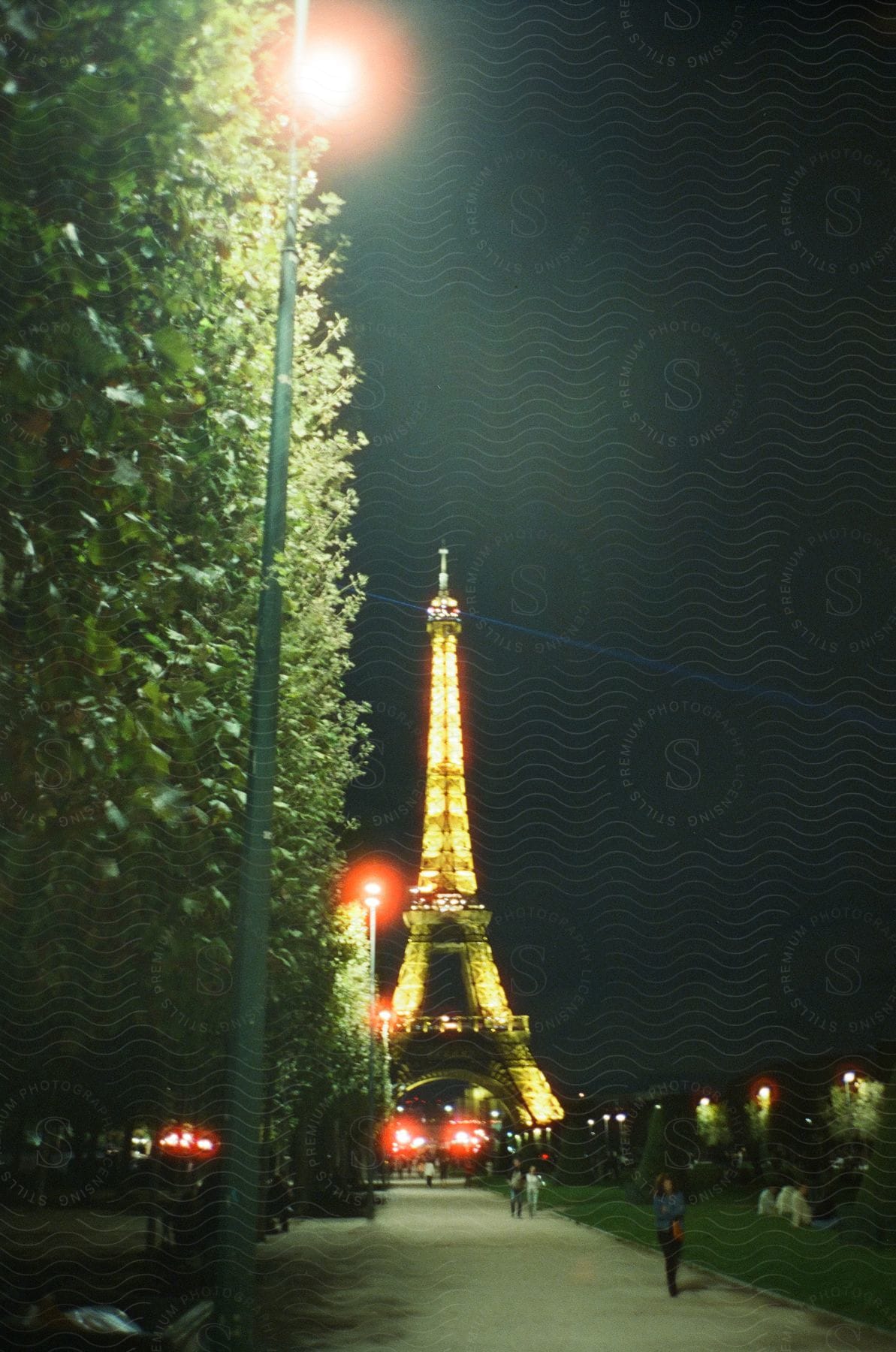 Eiffel tower at night with pedestrians and tourists around