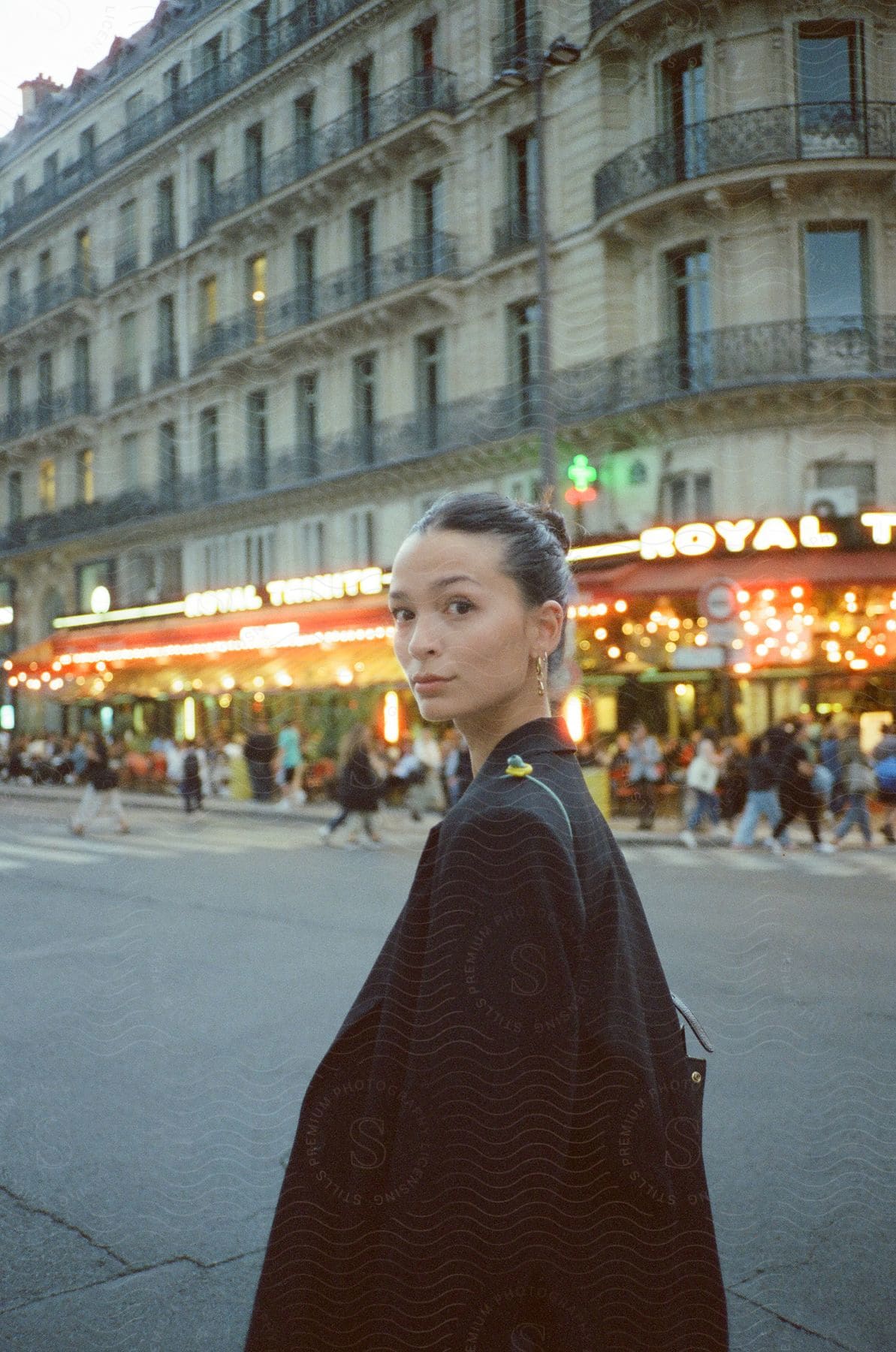 Woman posing for photo on busy street with red neon building facade in paris