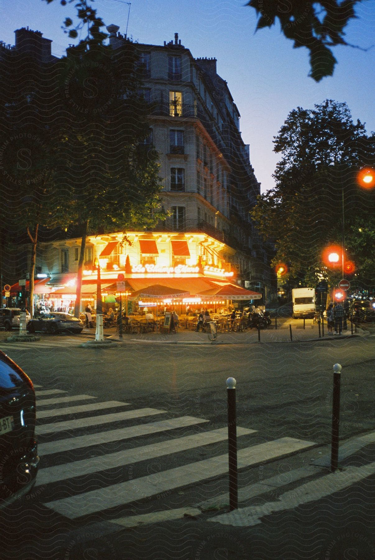 A crowded city street at dusk with buildings and street lights