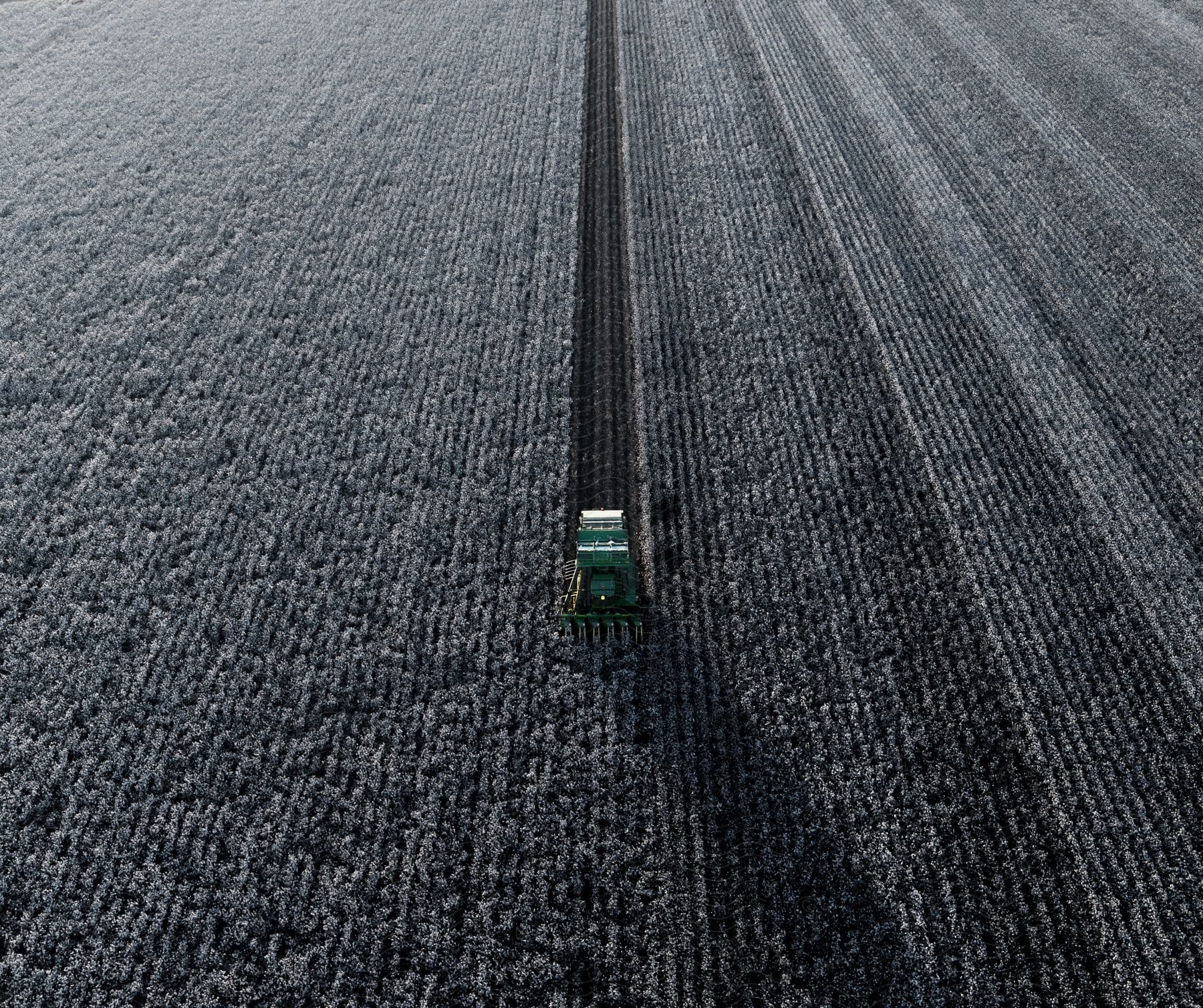 A green tractor plows a field in the countryside