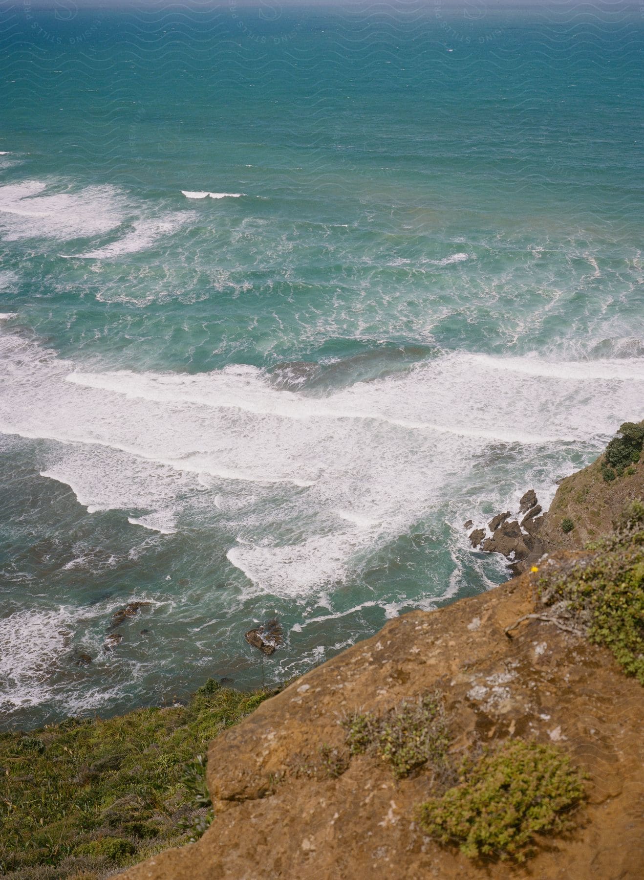 Waves crash against a rocky shoreline at muriwai or te henga beaches in auckland