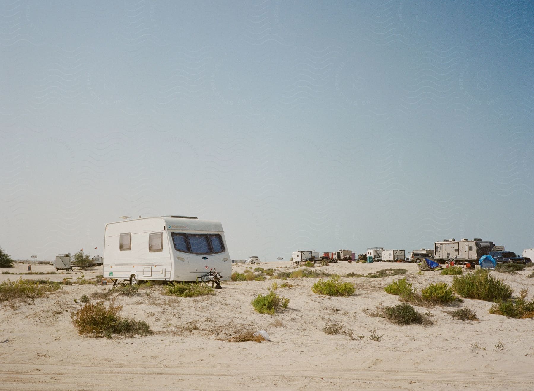 Rvs parked among sand dunes and brush in dubais manmade beach