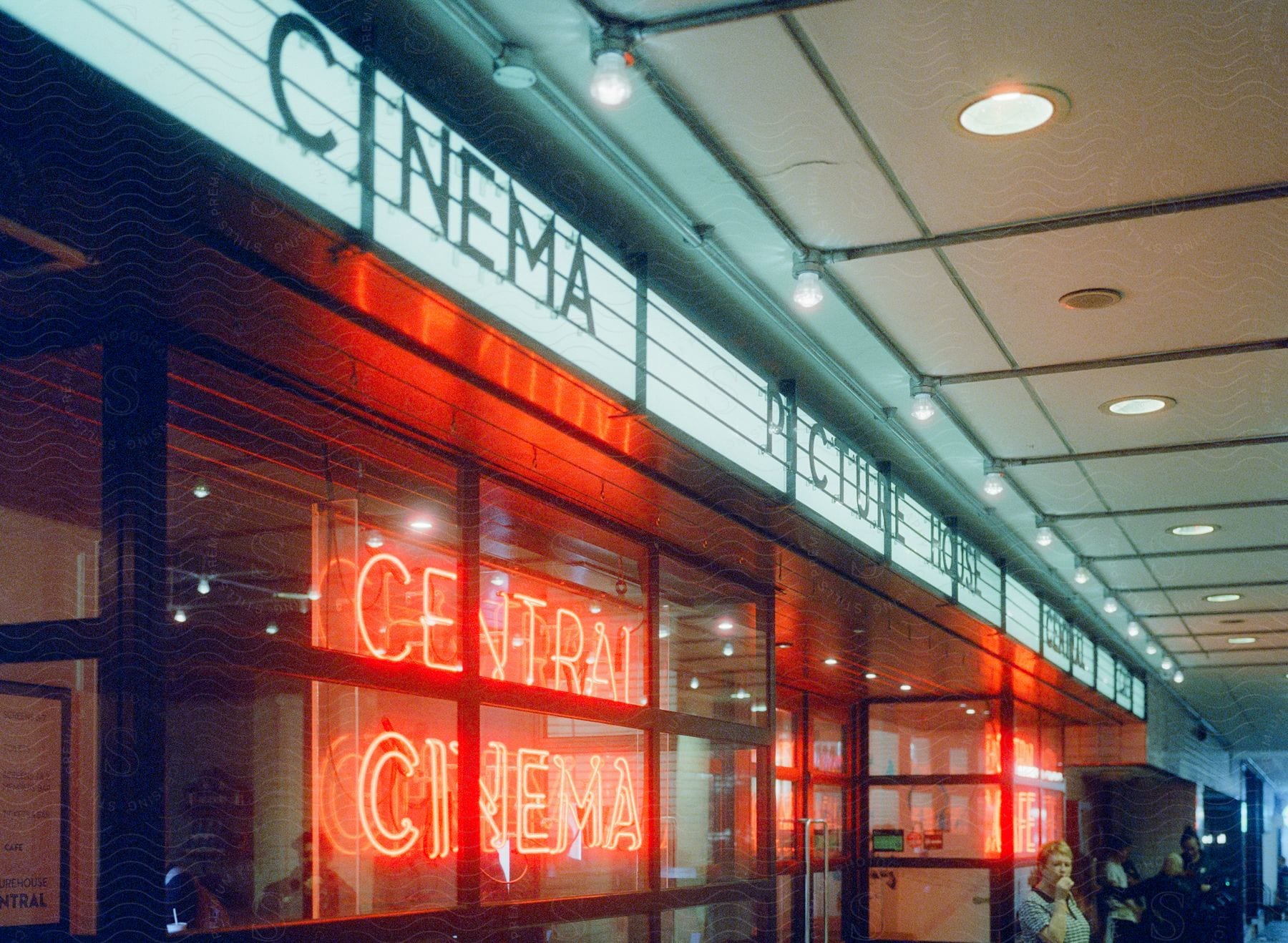 Cinema storefront with neon signs and white and black cinema signs in london