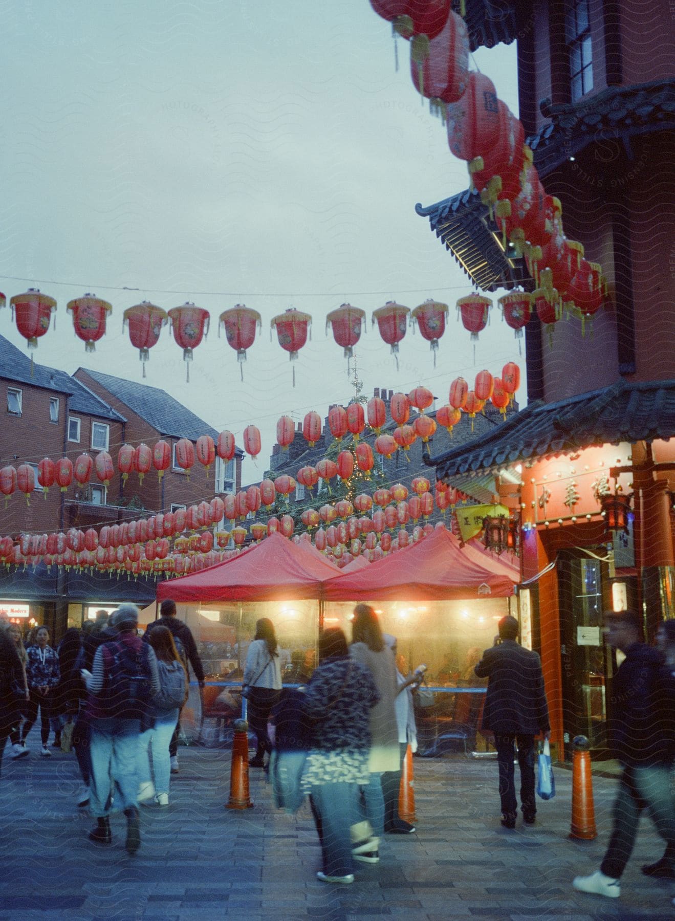 Buildings in a chinese town proudly display chinese inscriptions while multiple chinese lamps hang across the streets