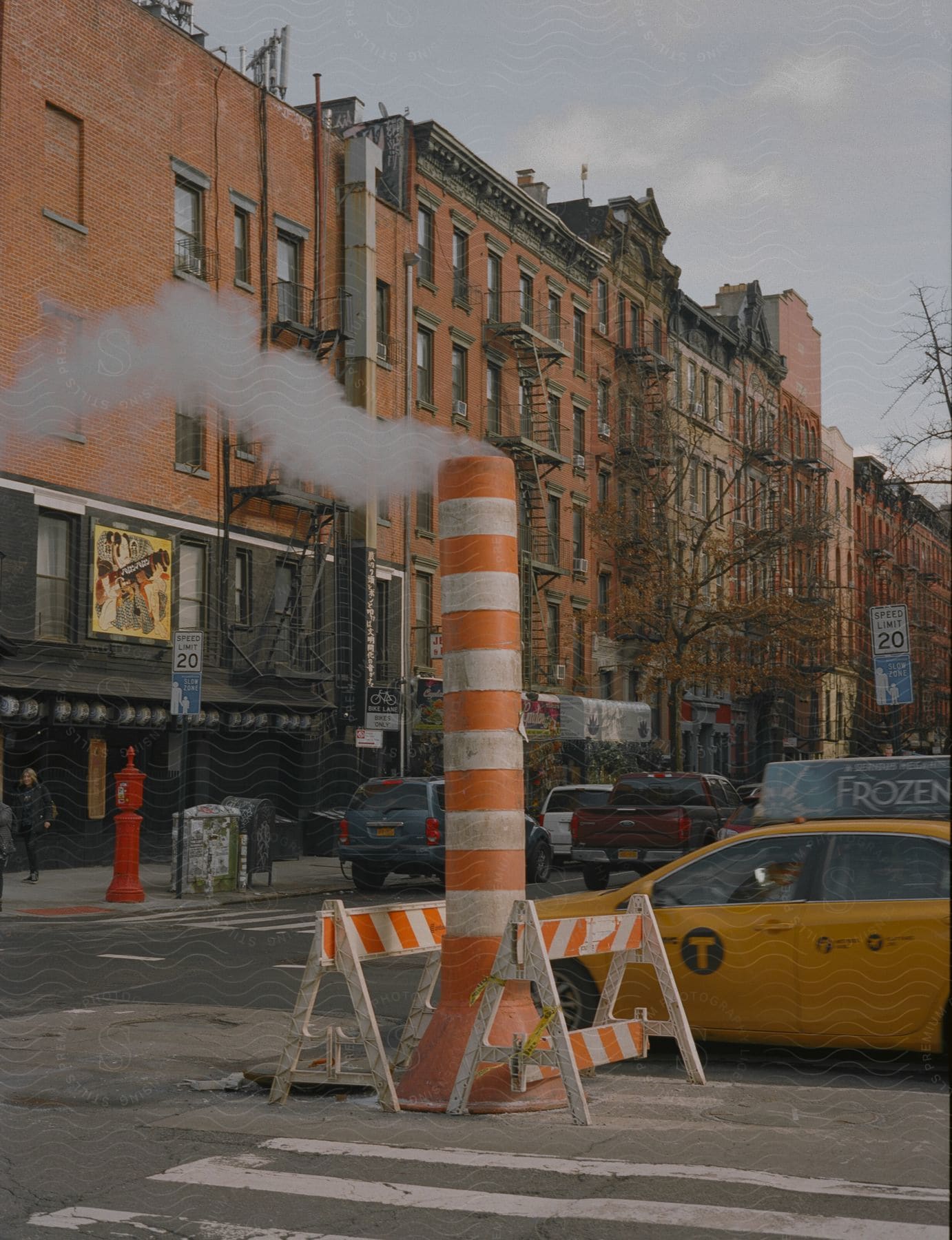 A community with an old building cars moving and a pole evoking smoke in new york