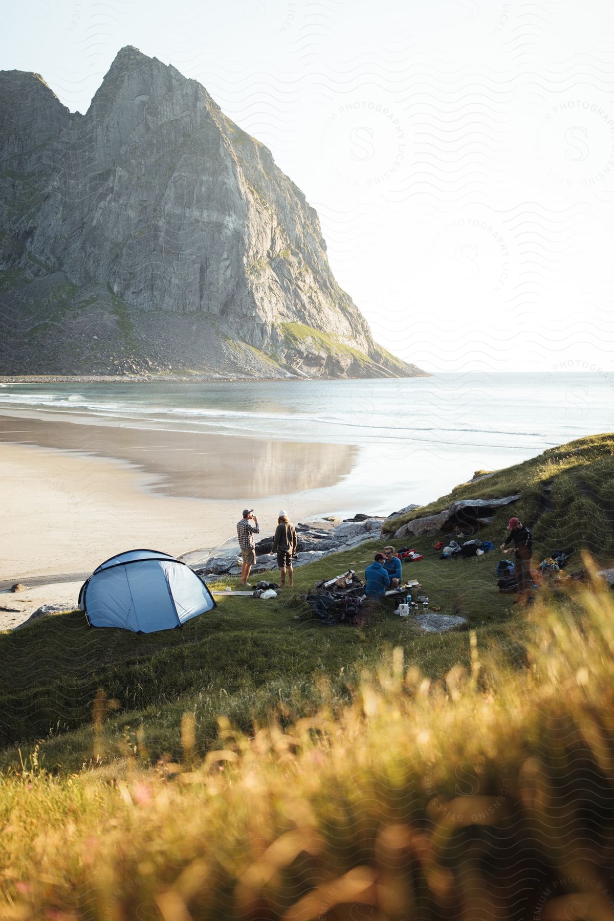 Small Group Of Men Camping At A Field Next To Kvalvika Beach