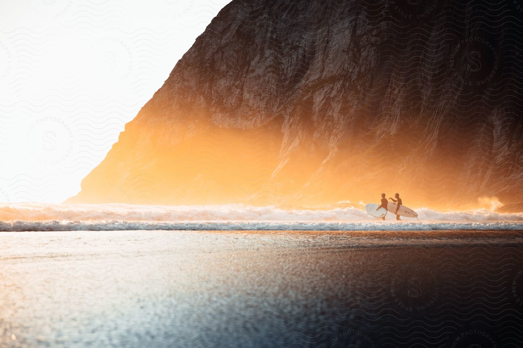 Two People Stand In The Ocean Holding Ski Boards Enjoying Water Sports At Dusk