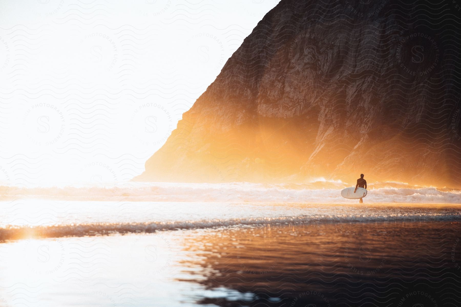 A person standing in the water with a surfboard