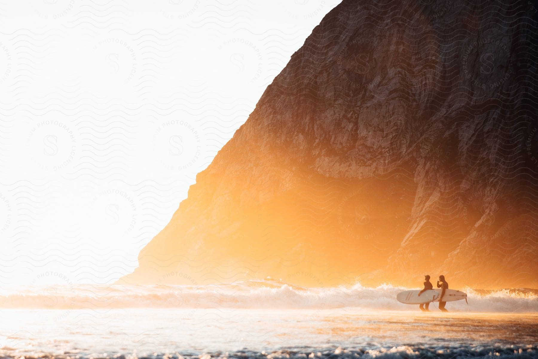 Two men walking purposefully towards the beach with ski boards in hand