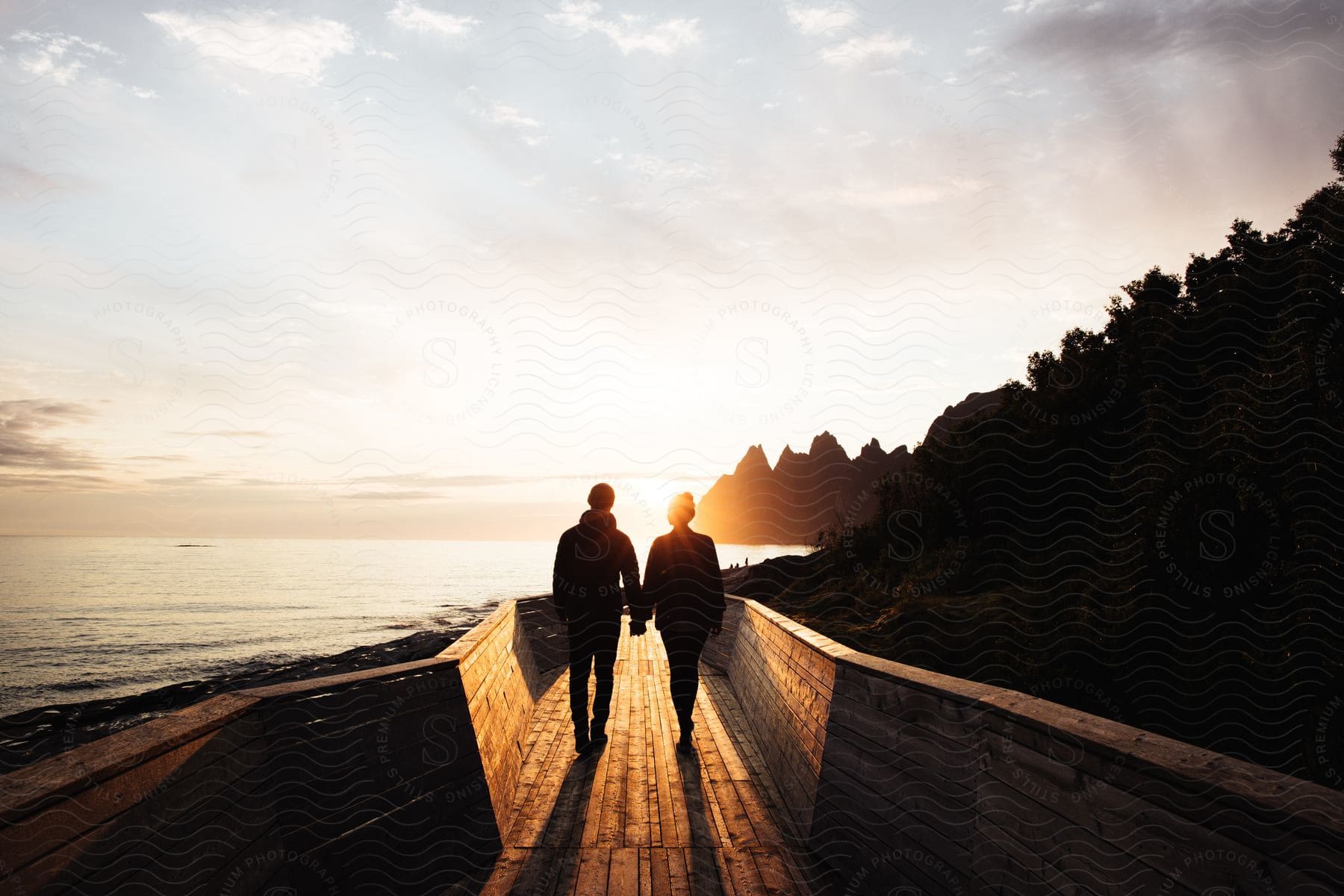 Two people walking along a waterfront path at dusk with a happy atmosphere