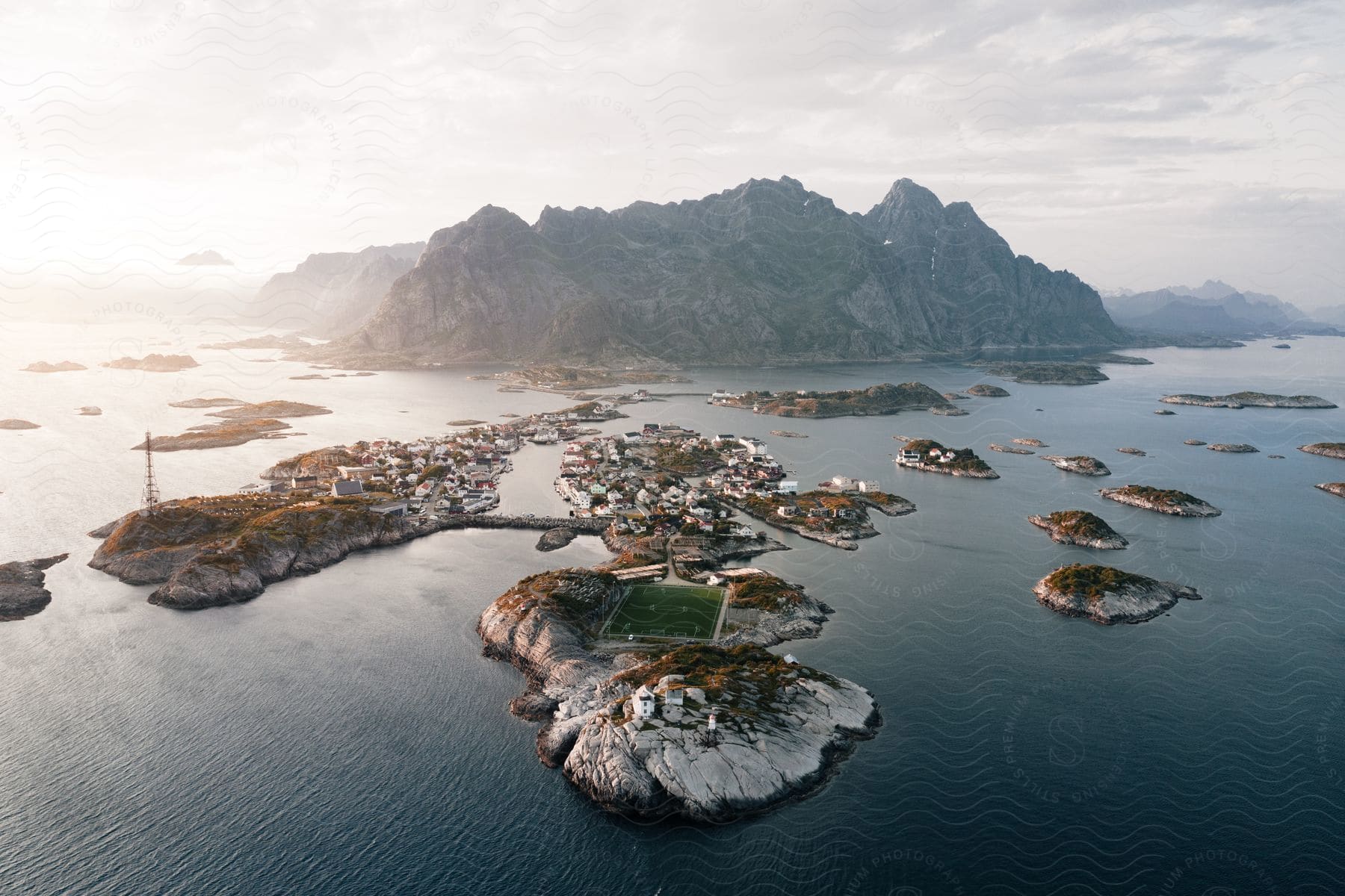 Aerial perspective of a small coastal town nestled among islands with rocky peaks in the background