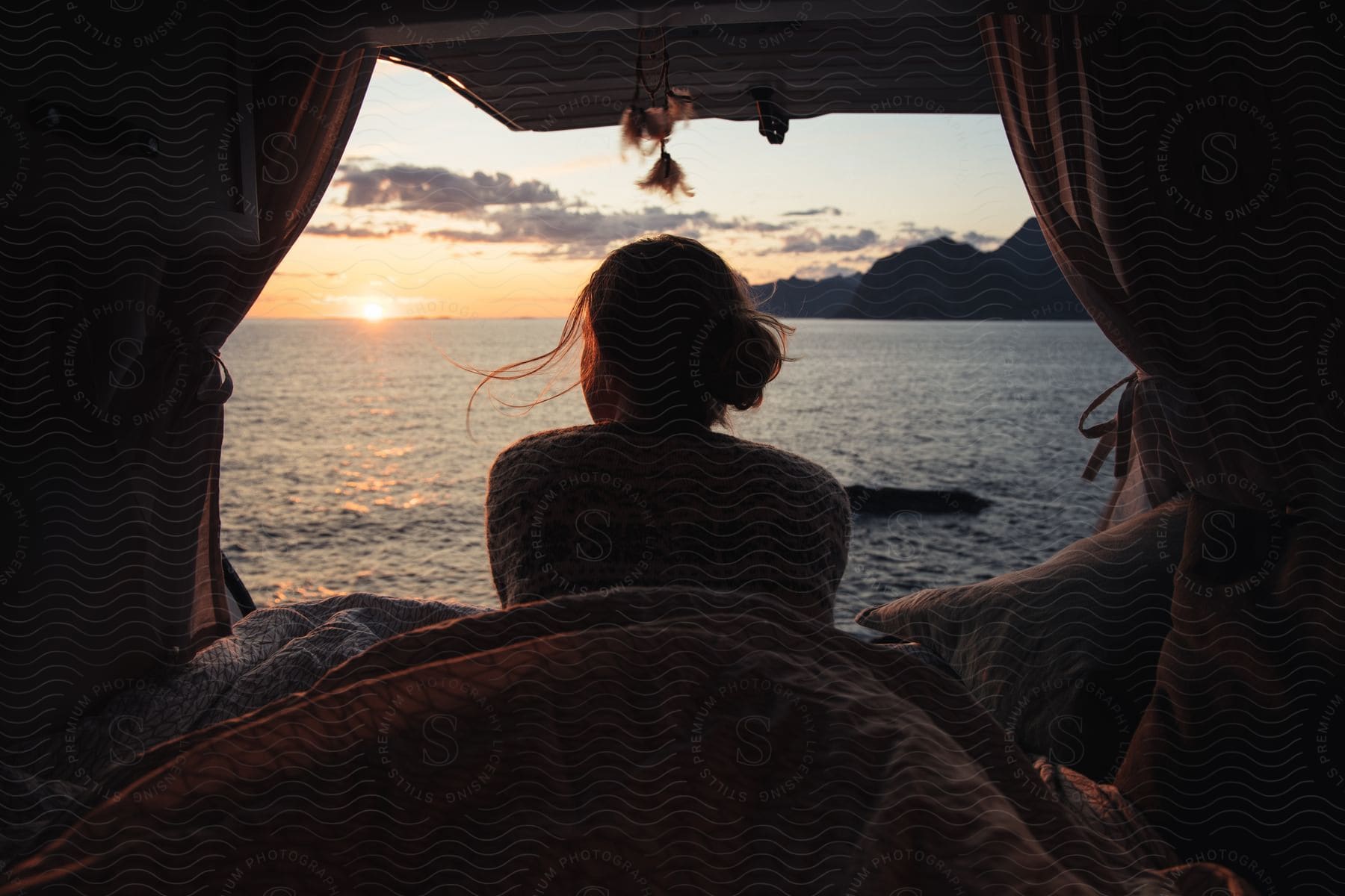 A woman finds shade and rest in a tent by a reflective water surface creating a tranquil scene