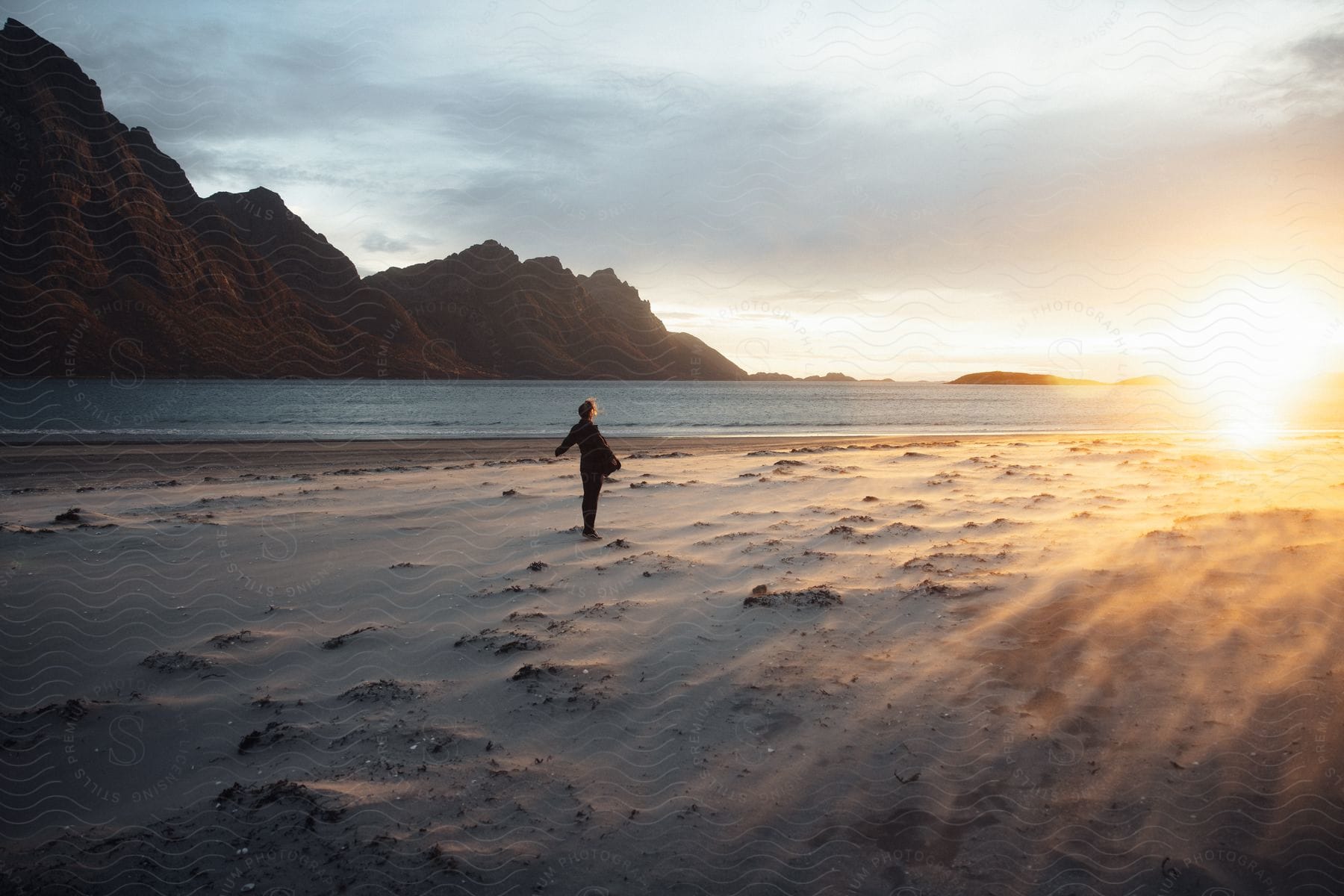 Woman posing at a beach during dusk or dawn with the sea and hills in the background