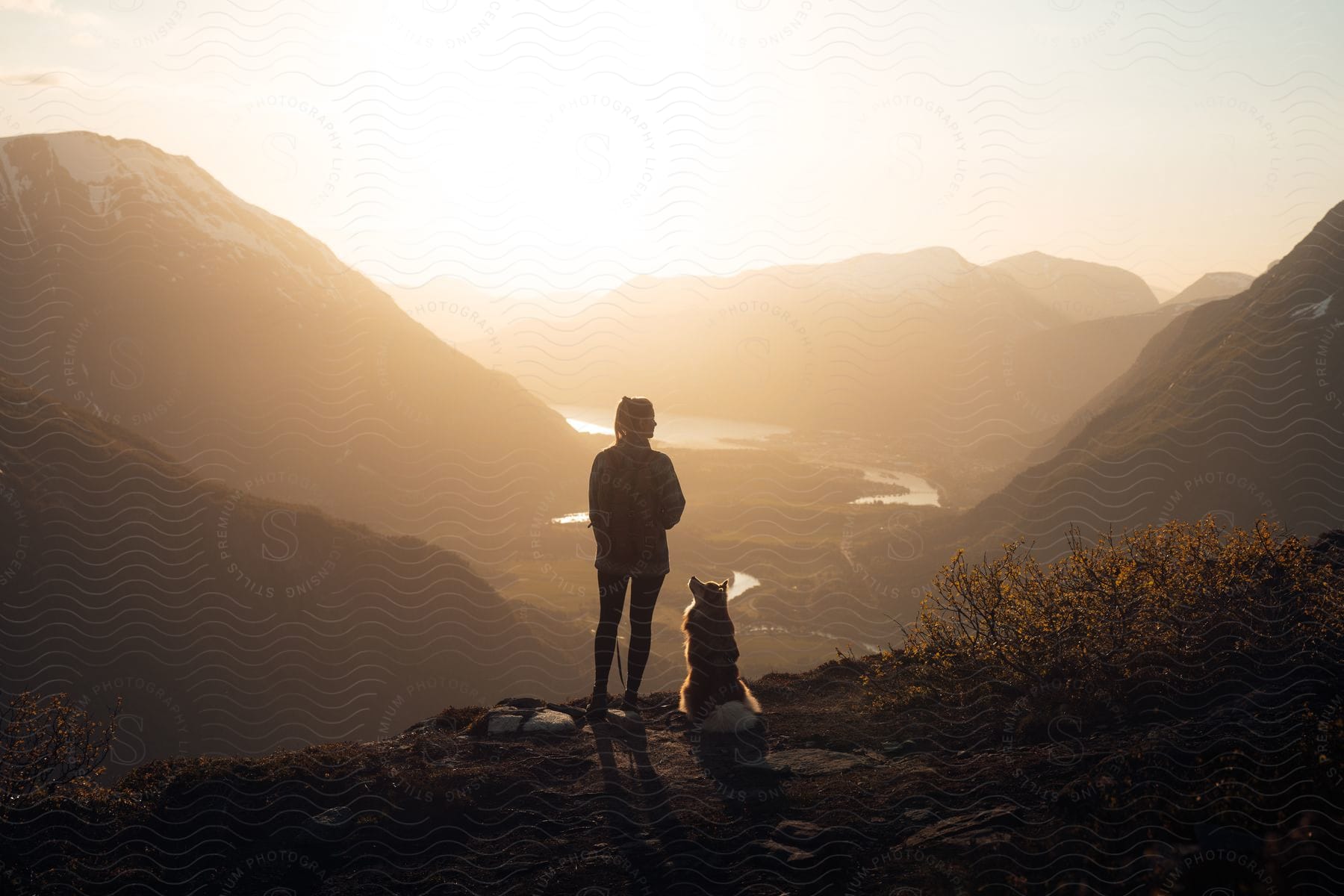 Woman and dog watching the sunset on the horizon in norway