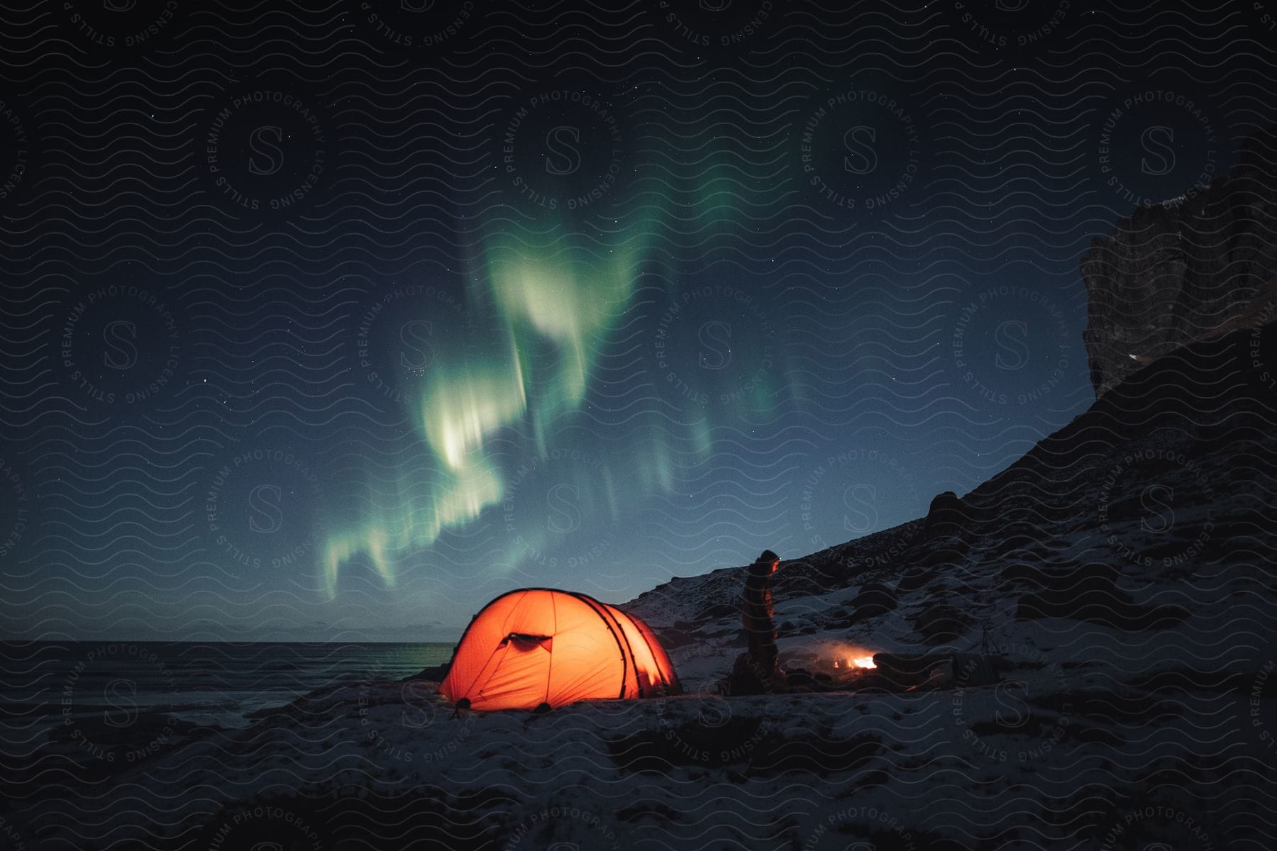 Stock photo of one person camping in a tent under a night sky in norway during winter