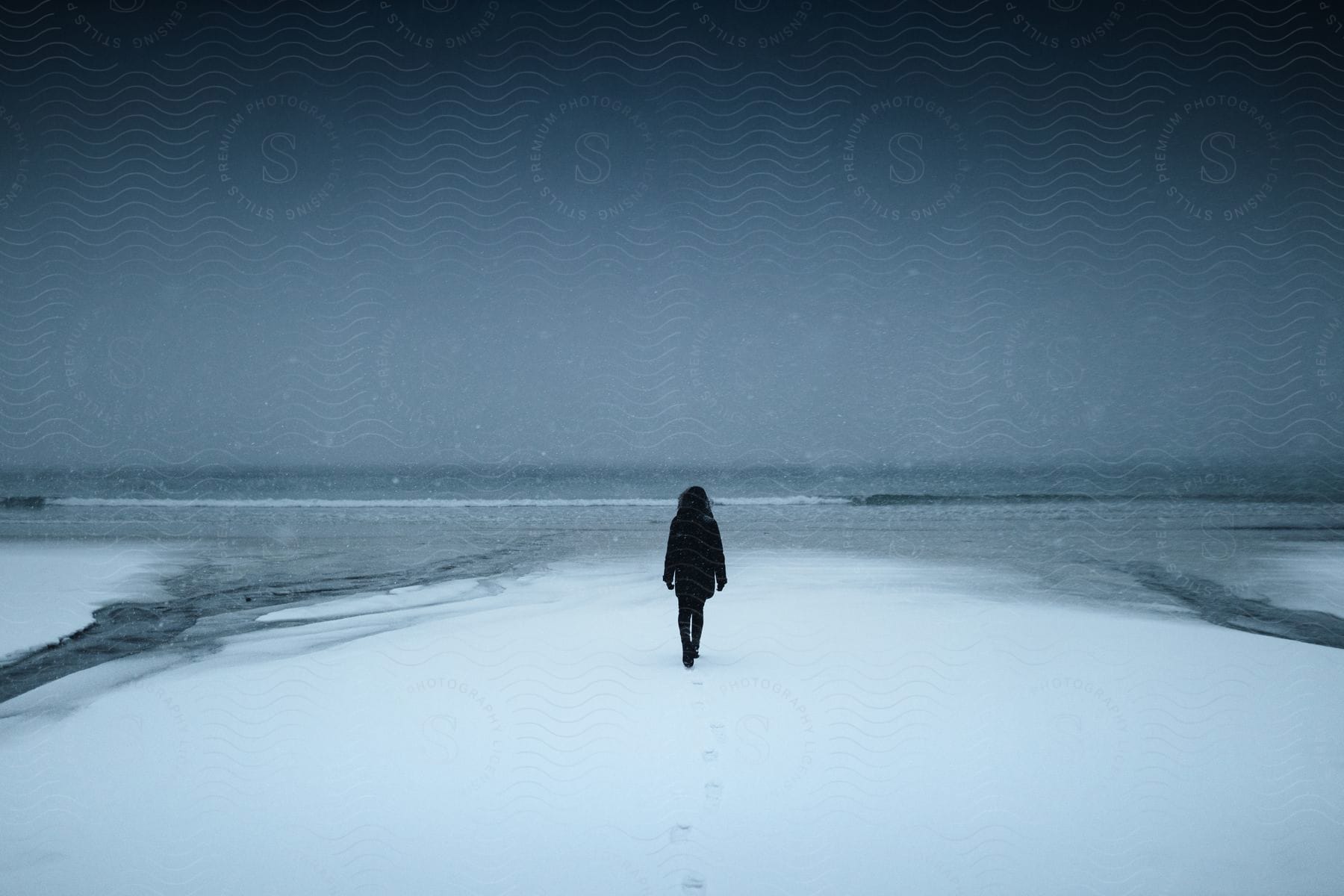 Person walking on snow towards the sea