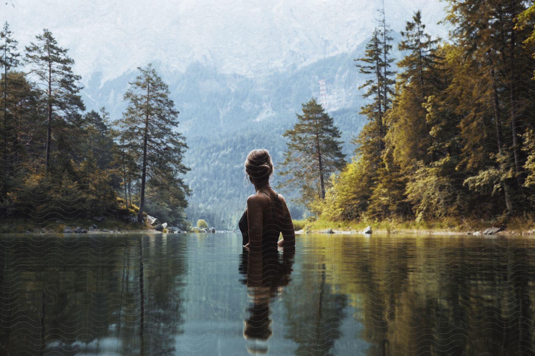 A woman in nature near a lake and mountains