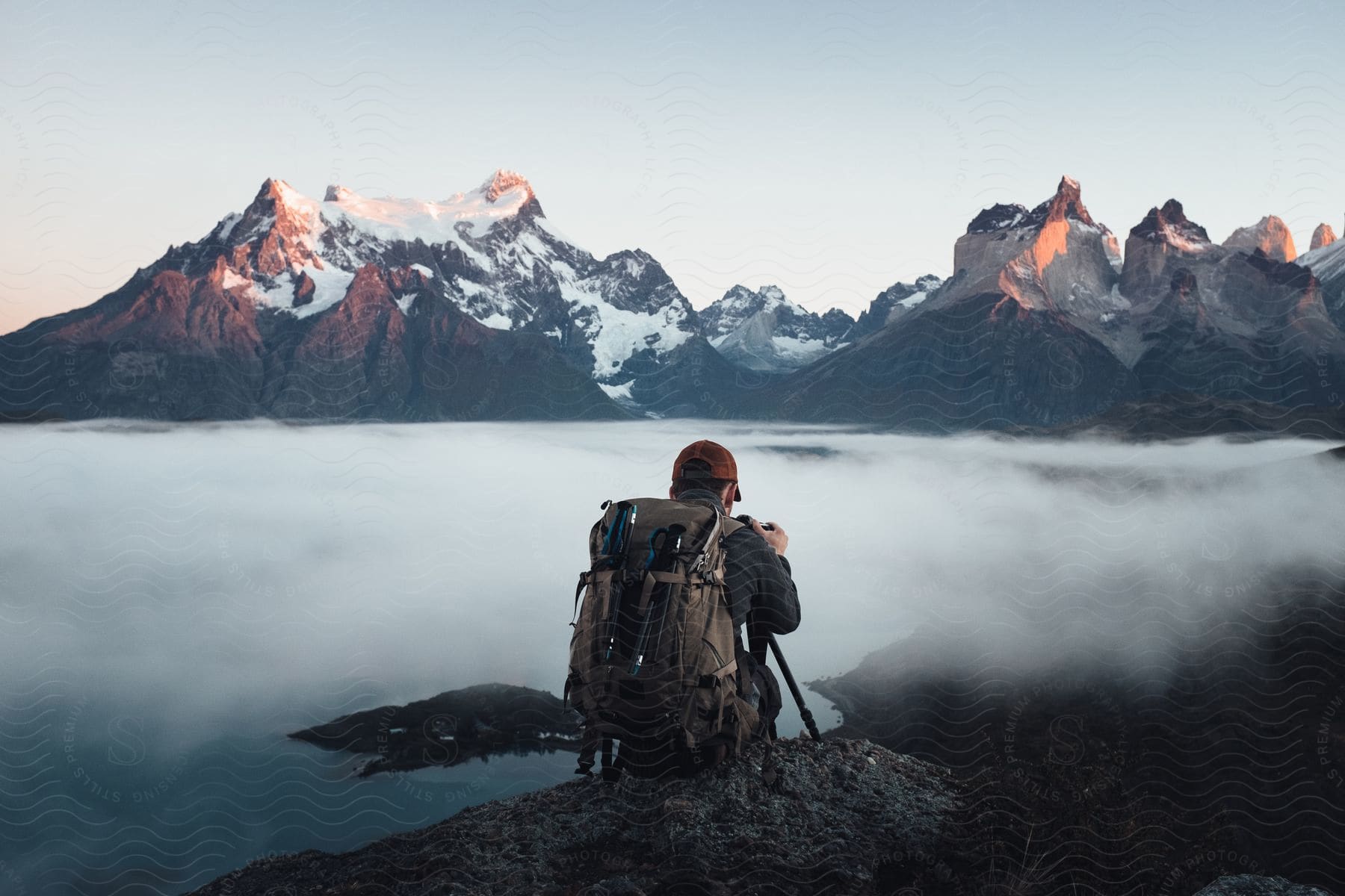 A person with a backpack trekking through a mountainous landscape with water in the background