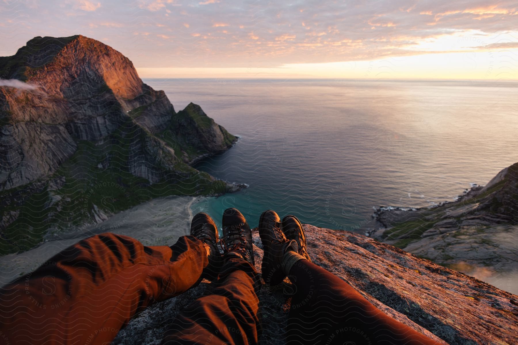 Two people sitting on a cliff gazing at the ocean