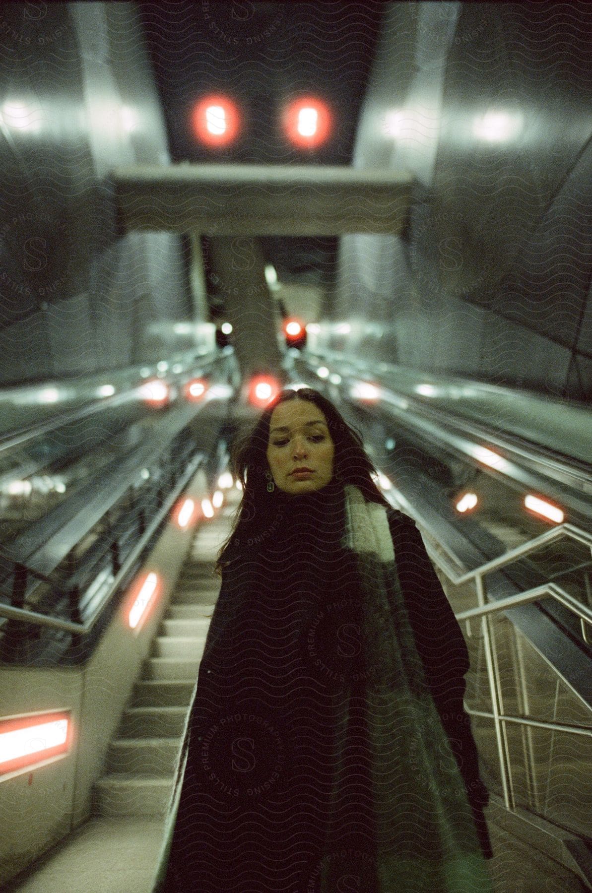 Stock photo of a woman standing at the base of stairs and escalators