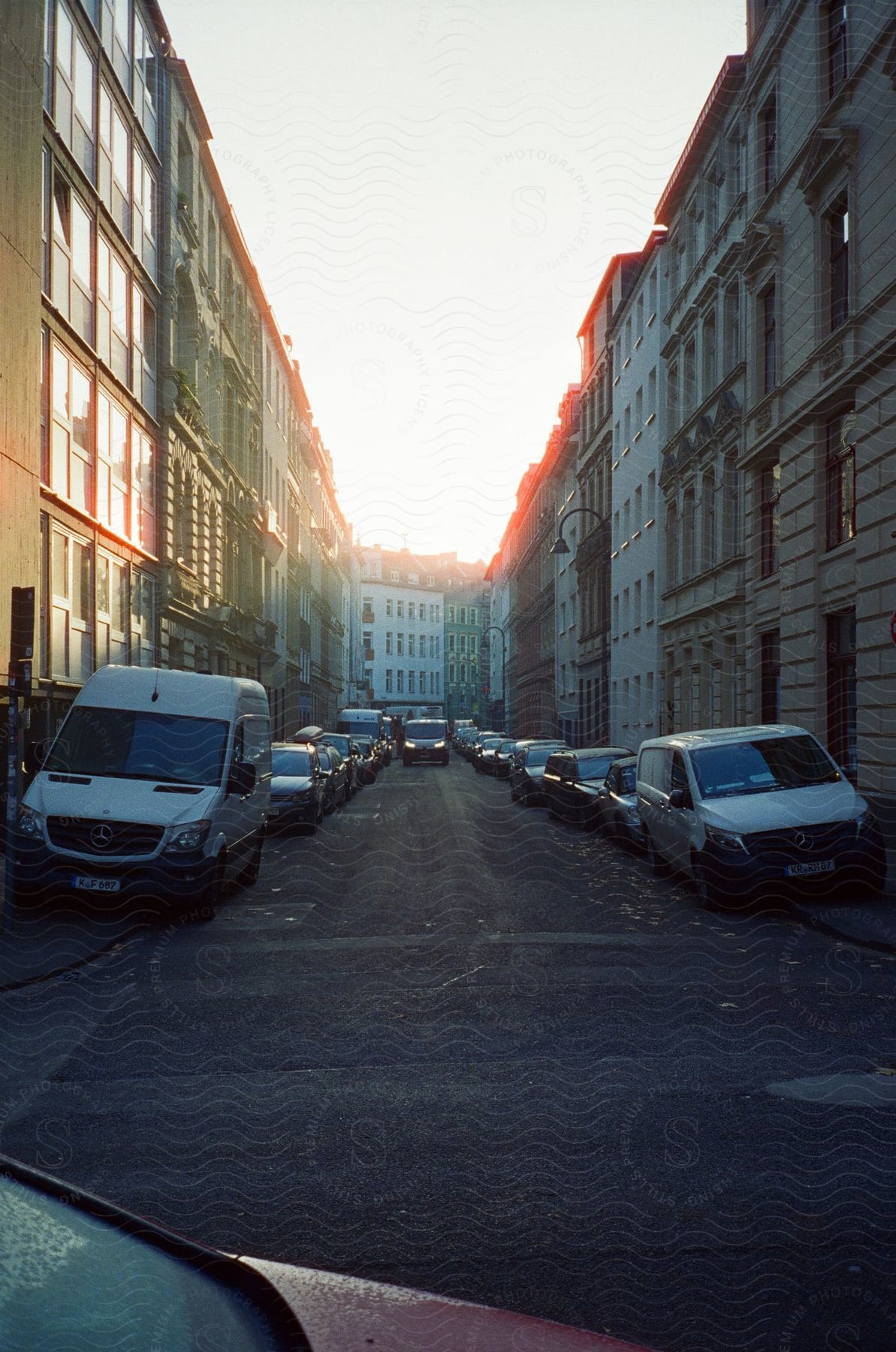 A city street with tall buildings and parked cars on either side