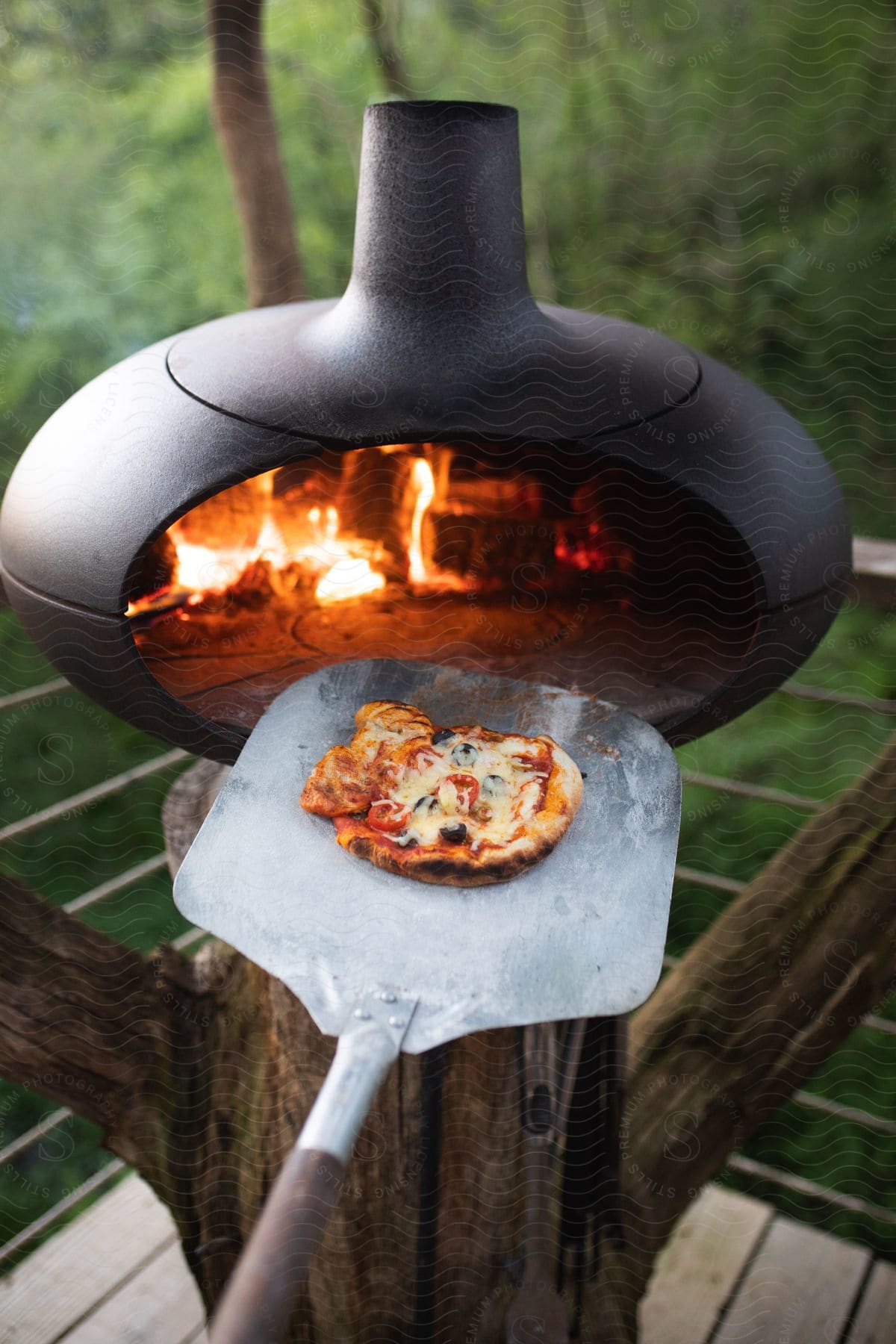 Someone making pizza outdoors over a fire