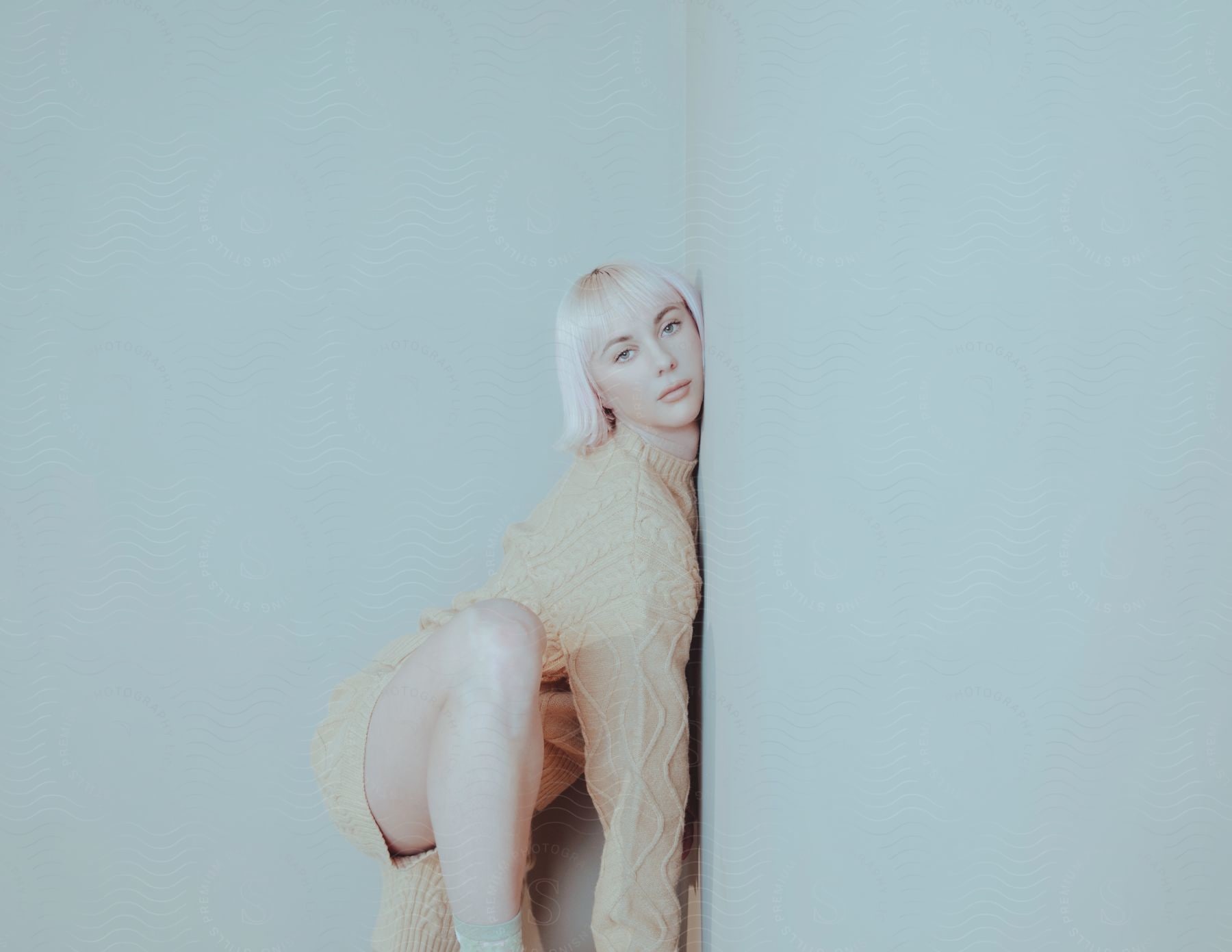A woman posing next to a blank wall indoors
