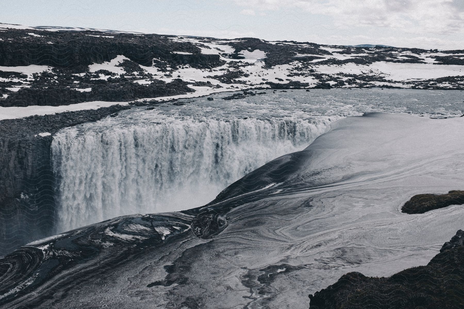 Ocean waves crashing against a towering waterfall creating a mesmerizing display of water cascading into a pool below