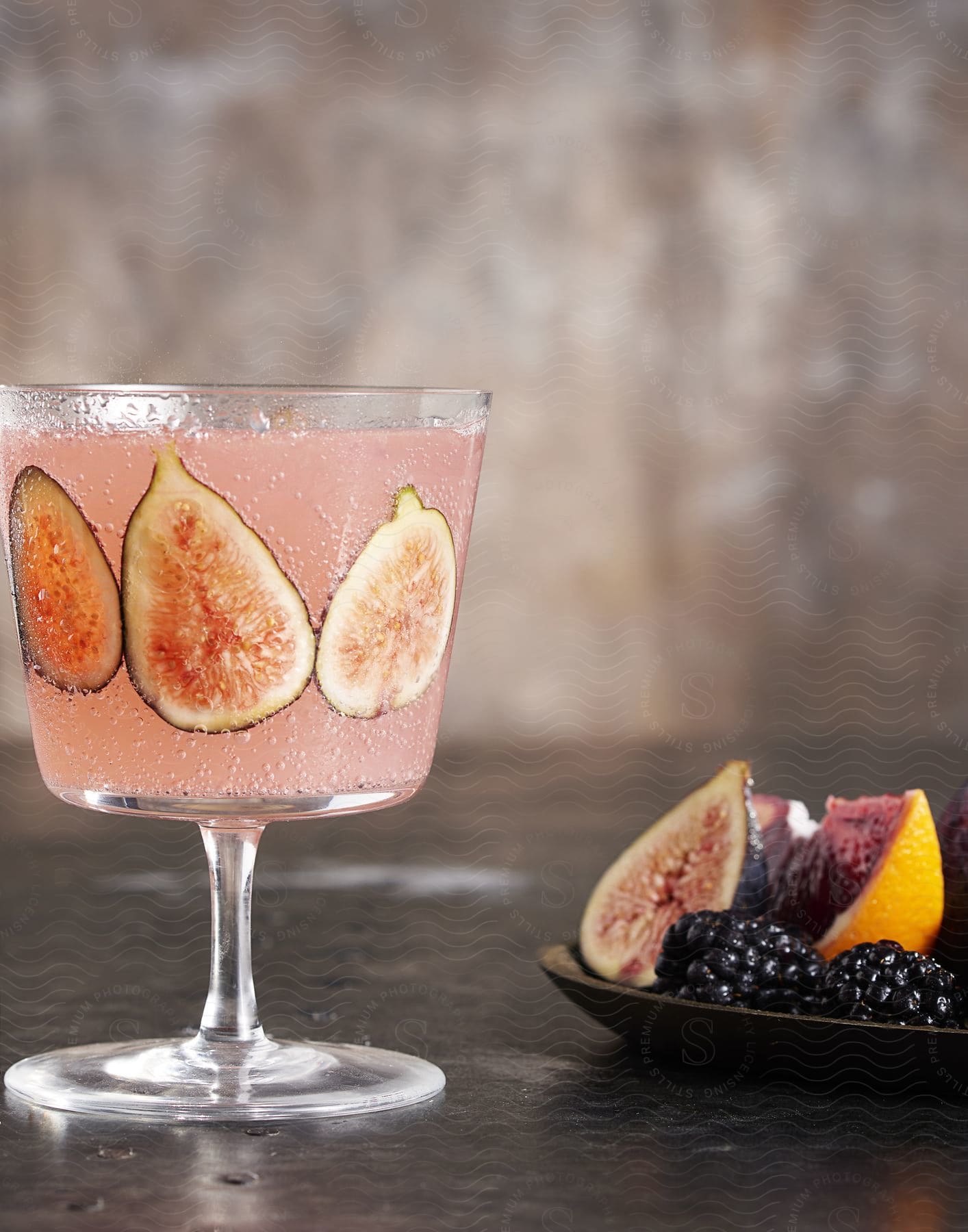 Stock photo of stemmed glass of pink beverage next to a plate of fruit