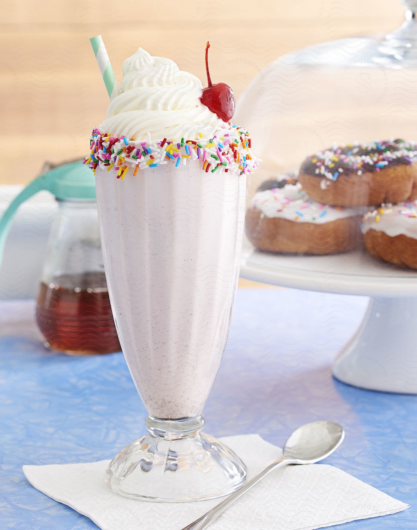 A milkshake three donuts under a glass protection and a honey jar