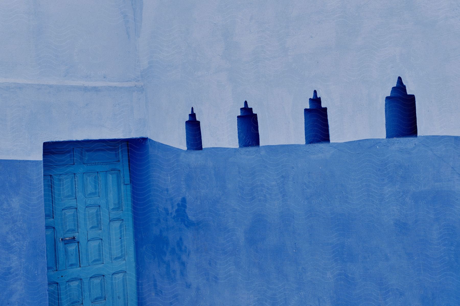 A building with white and blue concrete walls next to a blue wooden door