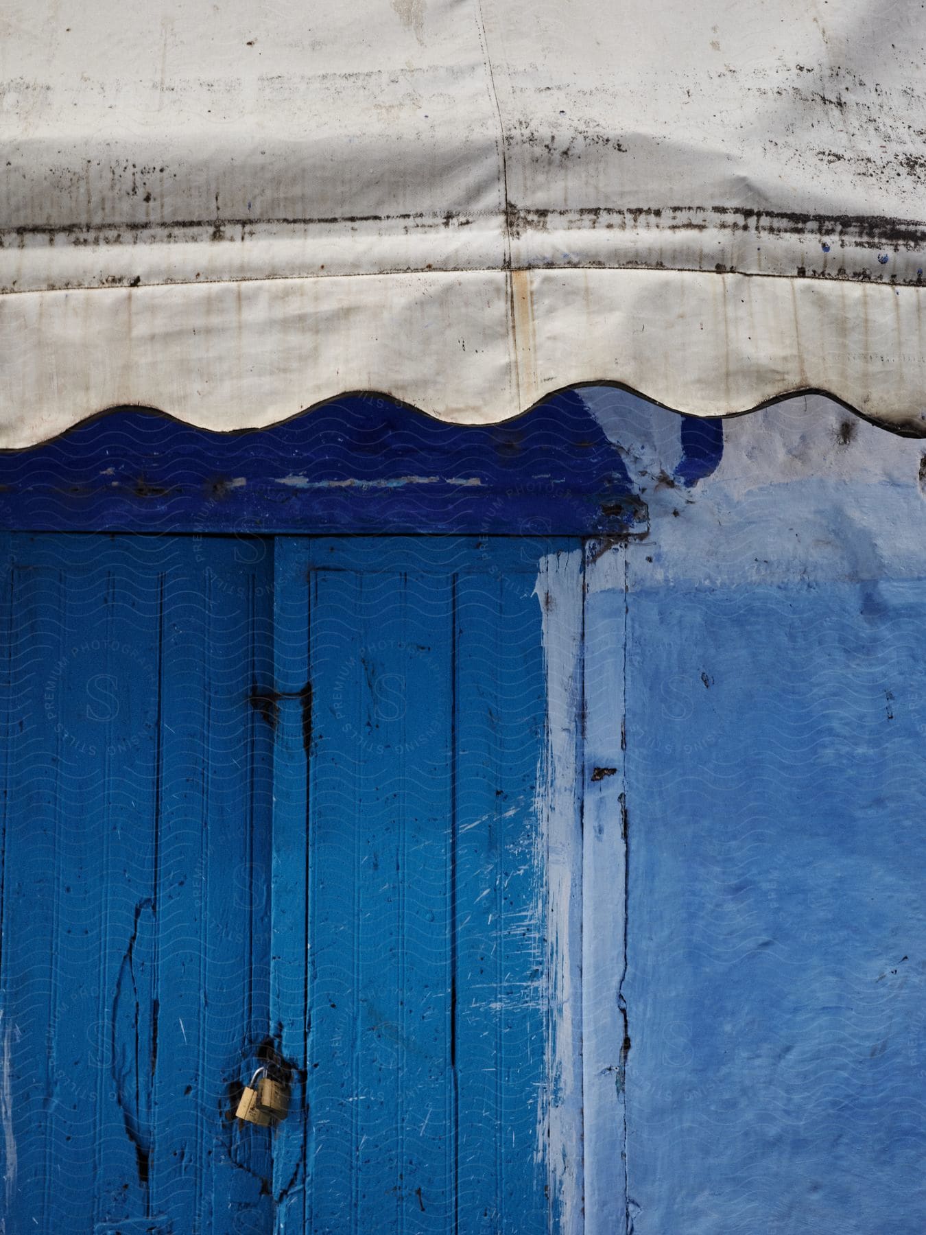 A locked wooden door painted blue with a white awning over it