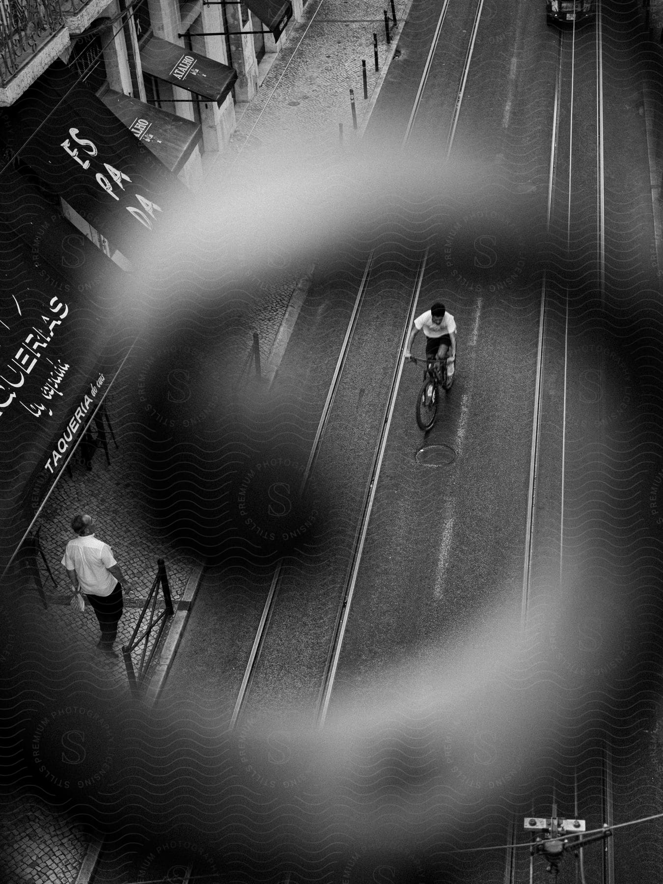 A man walks by as a boy rides his bike through a city street below