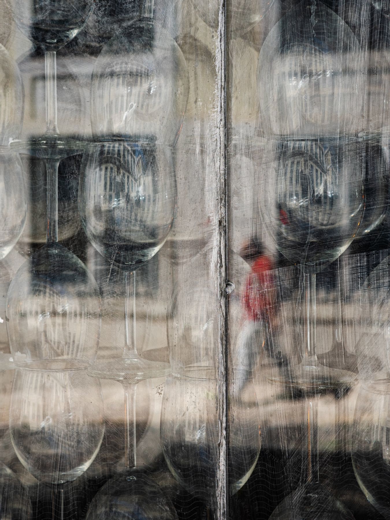 Glassware stacked in a window with the reflection of a person walking by